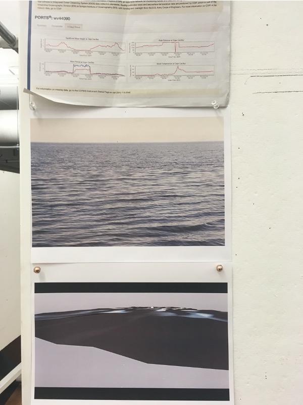 A scientific chart and pictures of waves are pinned to a wall.