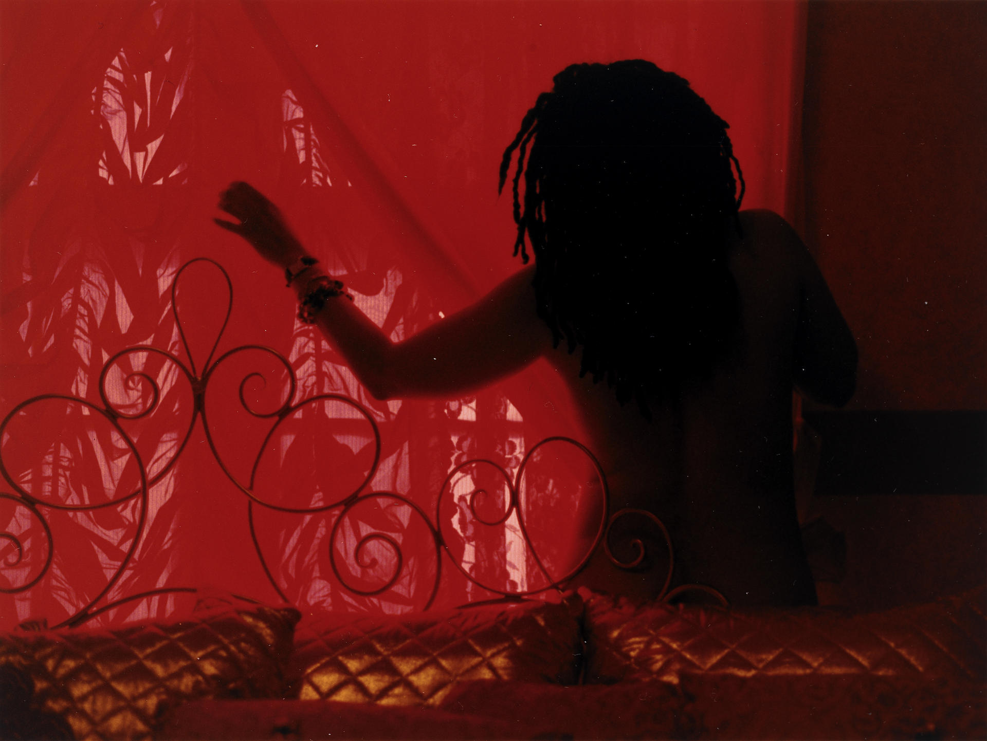 Photograph of a person with outstretched arm sillhouetted against a red window