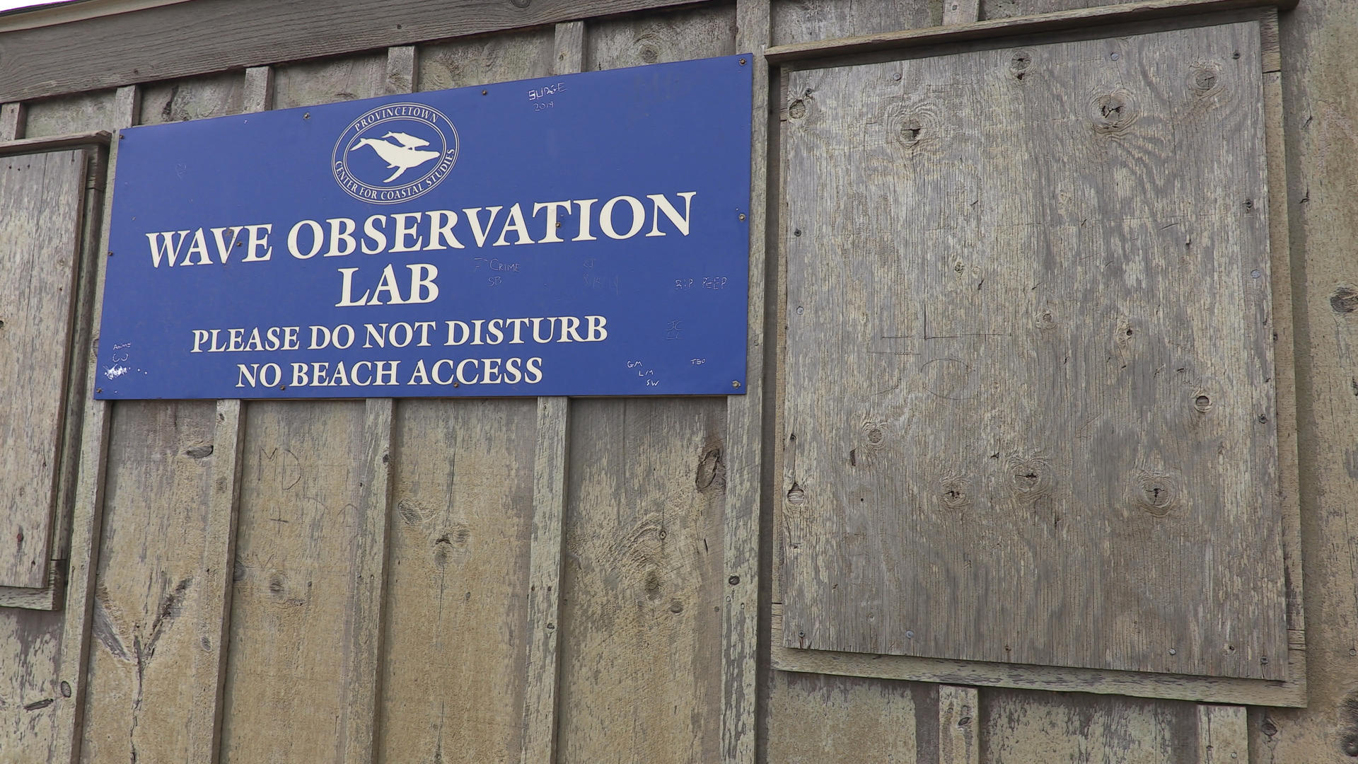 A sign on a wooden shed that states WAVE OBSERVATION LAB.