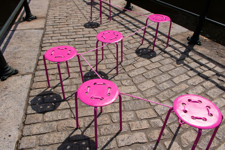 An image showing bright pink chairs tied together.