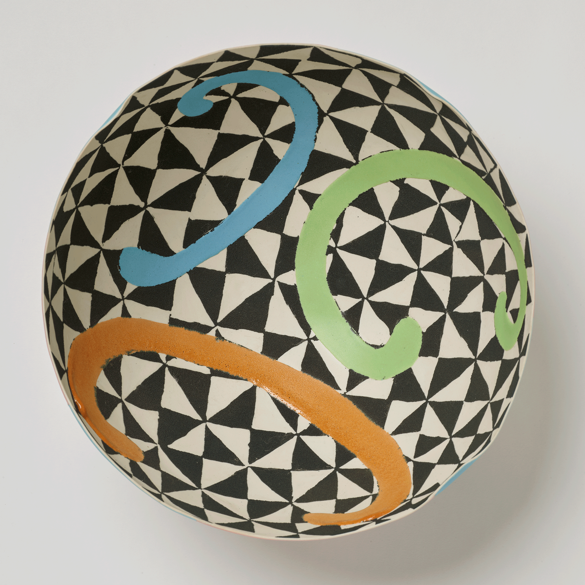 Interior view of bowl. Black and white geometric designs with three C-shapes on top in blue, green, and orange.