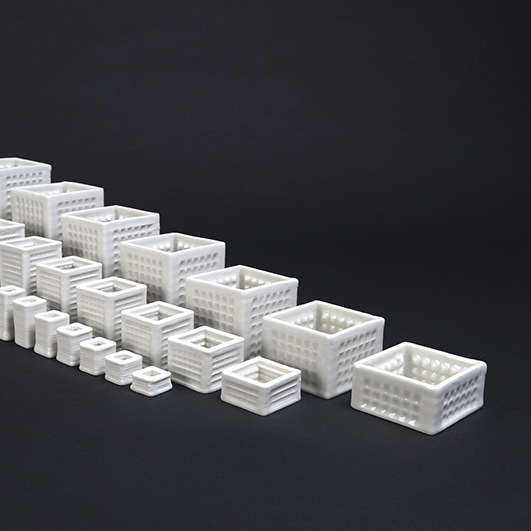 color photo; three row of progressively larger square milkcrate-like ceramics sit against a black background