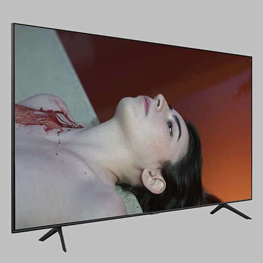 TV screen showing a white woman with dark hair lying down, from the chest up. She is naked and has blood spilling over her right shoulder