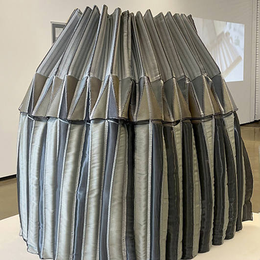 color photograph of a heavy metallic fabric pleated into a large vessel
