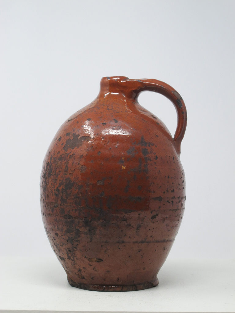 /A%20bulbous%20orange%20ceramic%20jug%20with%20a%20handle.%20