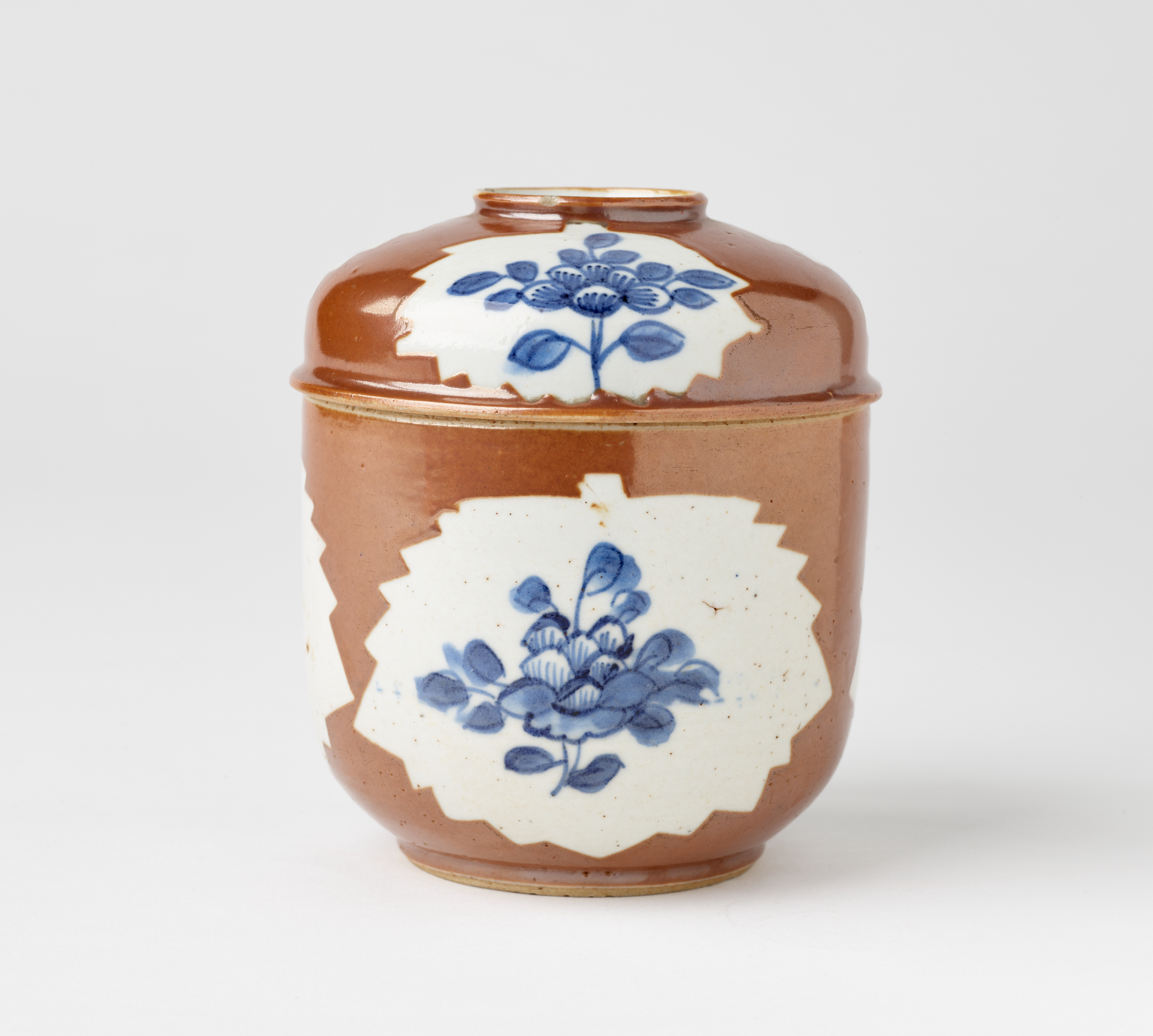 /A%20ceramic%20covered%20bowl%20that%20is%20white%2C%20brown%20and%20has%20blue%20floral%20decorations.