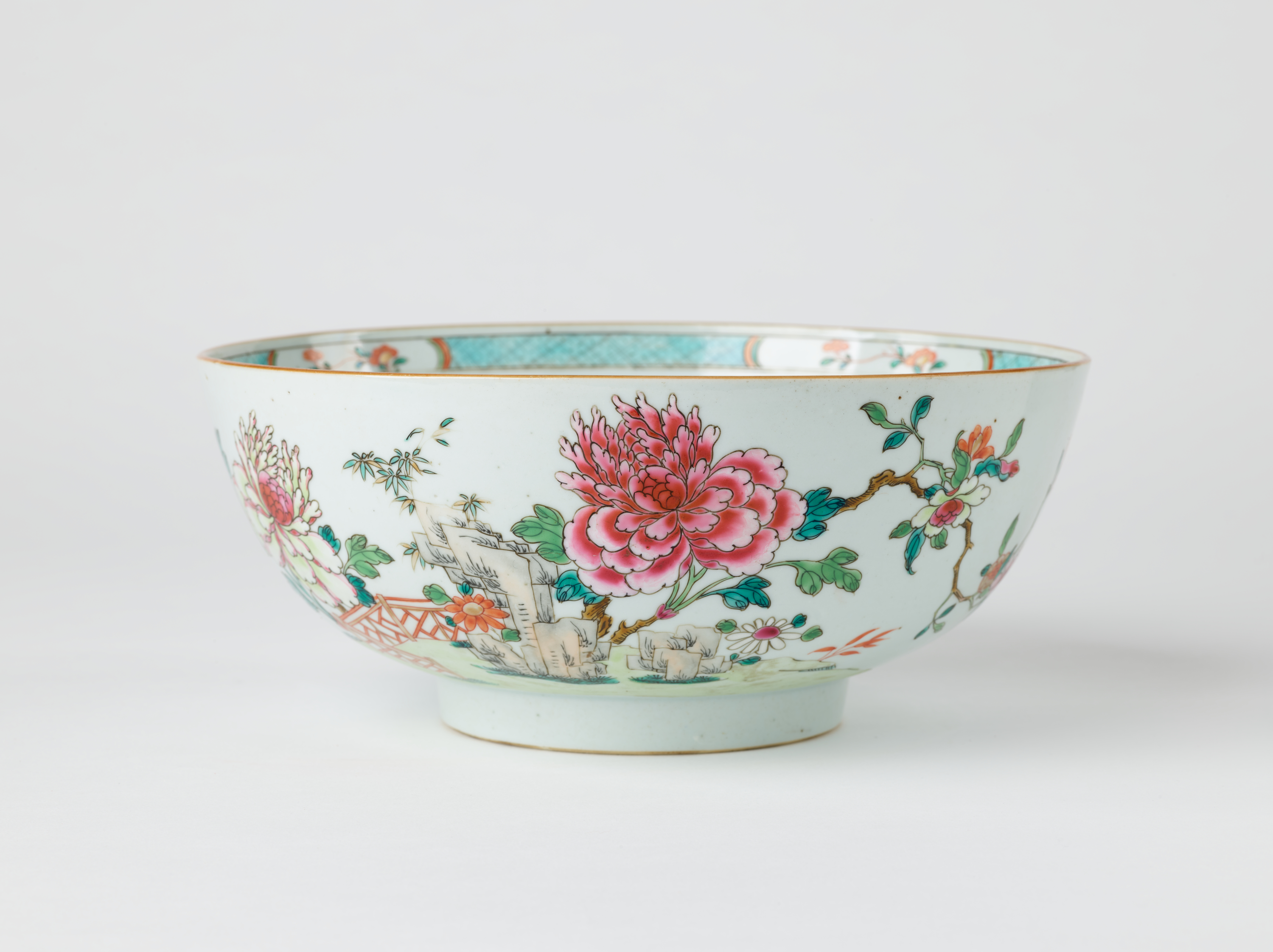 /A%20white%20ceramic%20punch%20bowl%20with%20a%20short%20foot%20and%20teal%2C%20green%2C%20pink%2C%20and%20red%20floral%20decorations%20along%20the%20body%20and%20inside%20of%20the%20vessel.%20