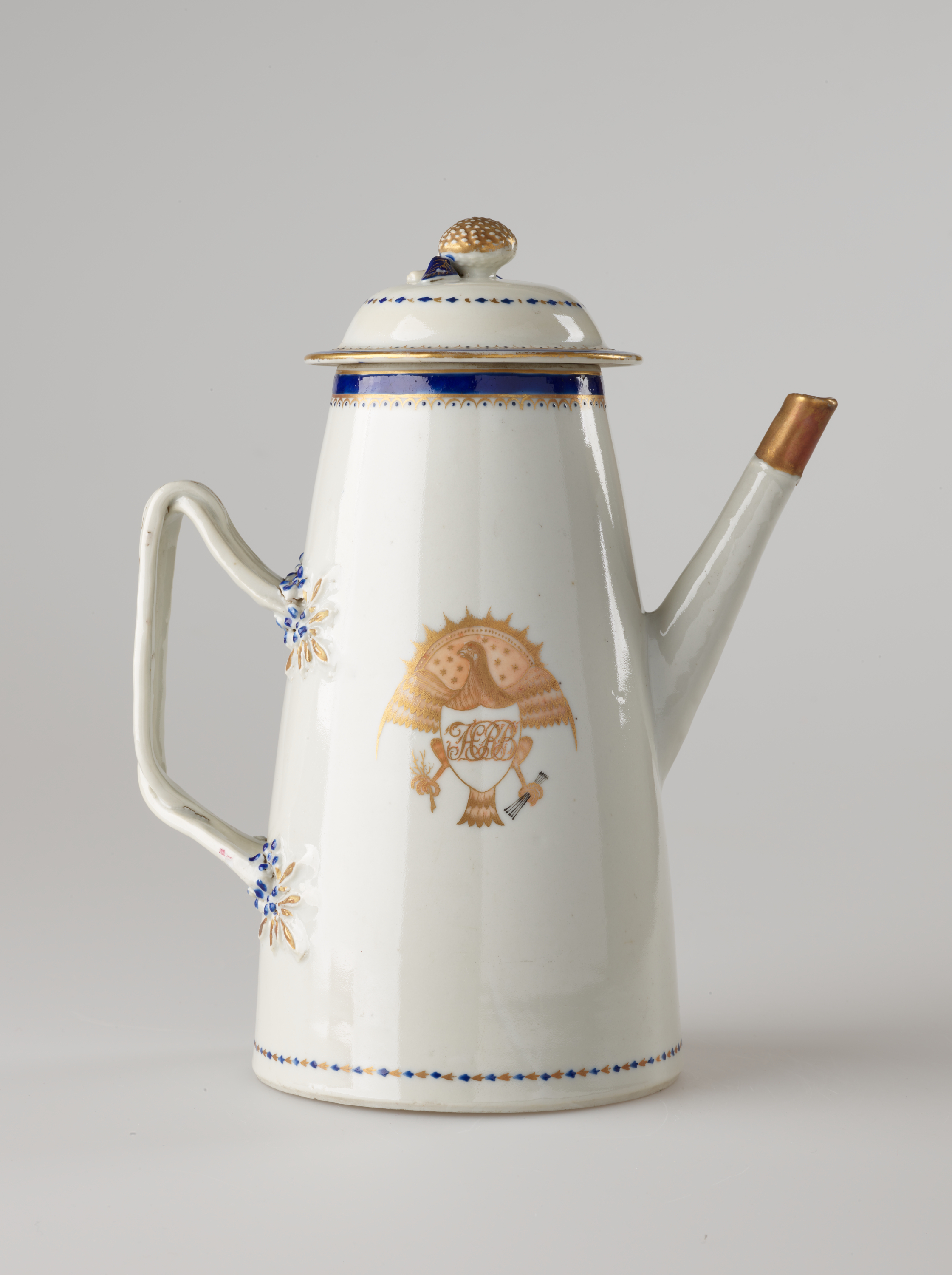 /A%20white%2C%20blue%20and%20gilded%20teapot%20with%20a%20long%20straight%20spout%2C%20a%20handle%2C%20and%20lid.%20The%20central%20decoration%20depicts%20a%20heraldry%20bird%20with%20a%20shield%20and%20objects%20in%20its%20talons.