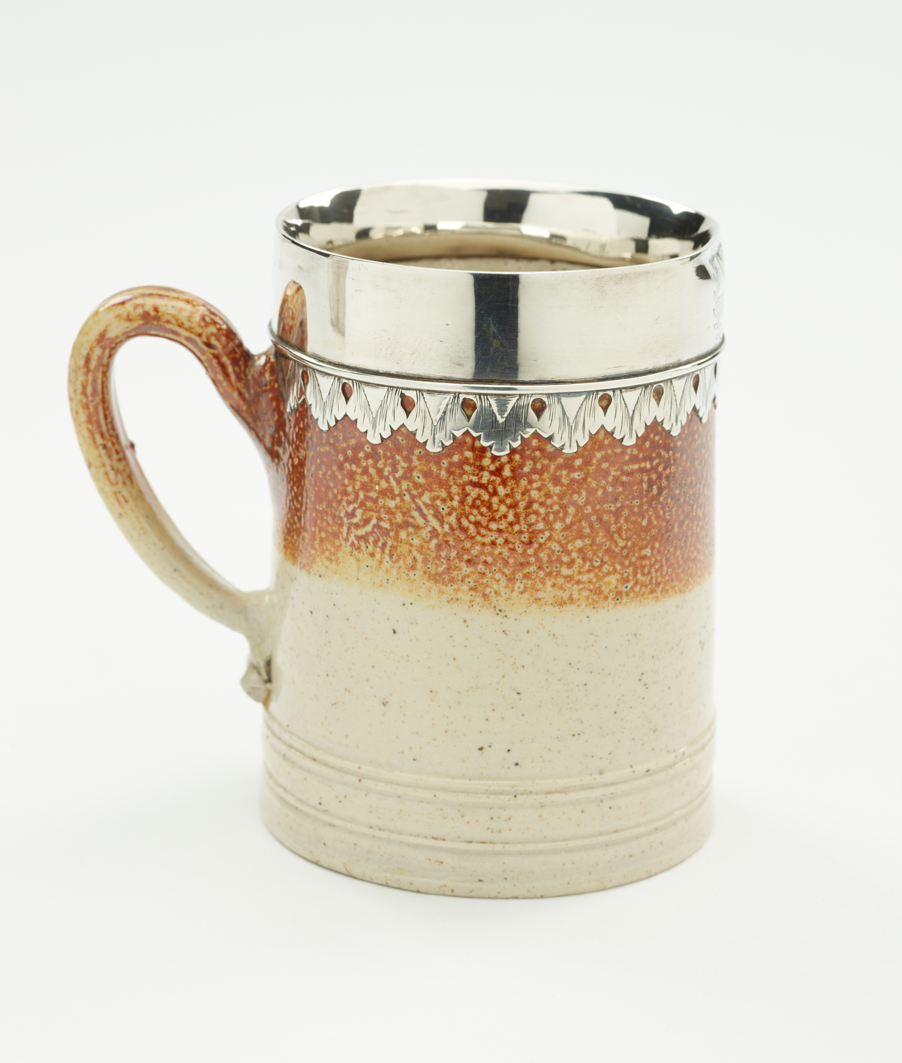 /A%20salt%20glaze%20and%20silver%20mug%20with%20vertical%20decorative%20elements%20and%20one%20handle.