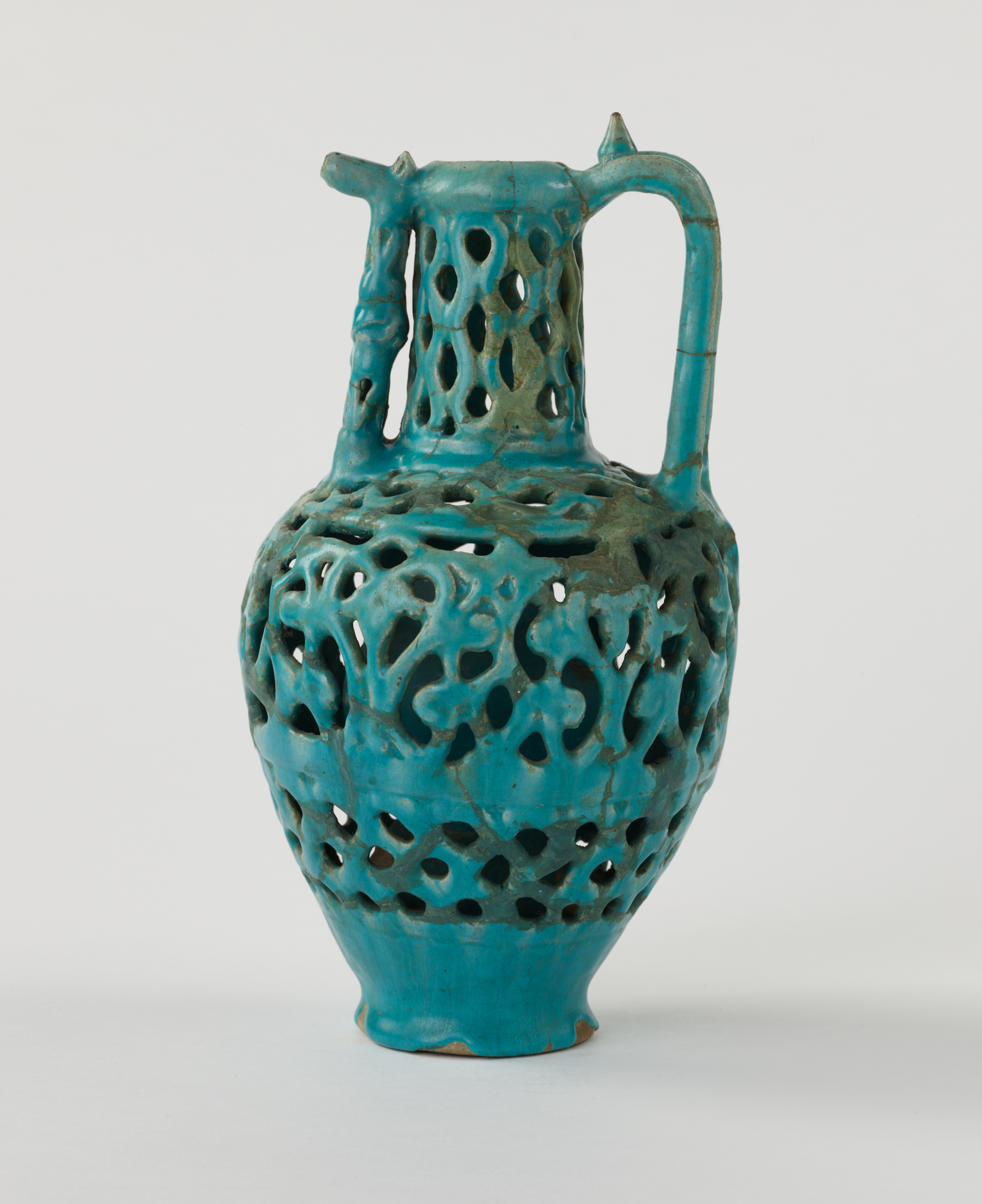 /A%20turquoise%20earthenware%20ewer%20with%20cut%20out%20decorations%20and%20a%20sculptural%20spout%20and%20handle.
