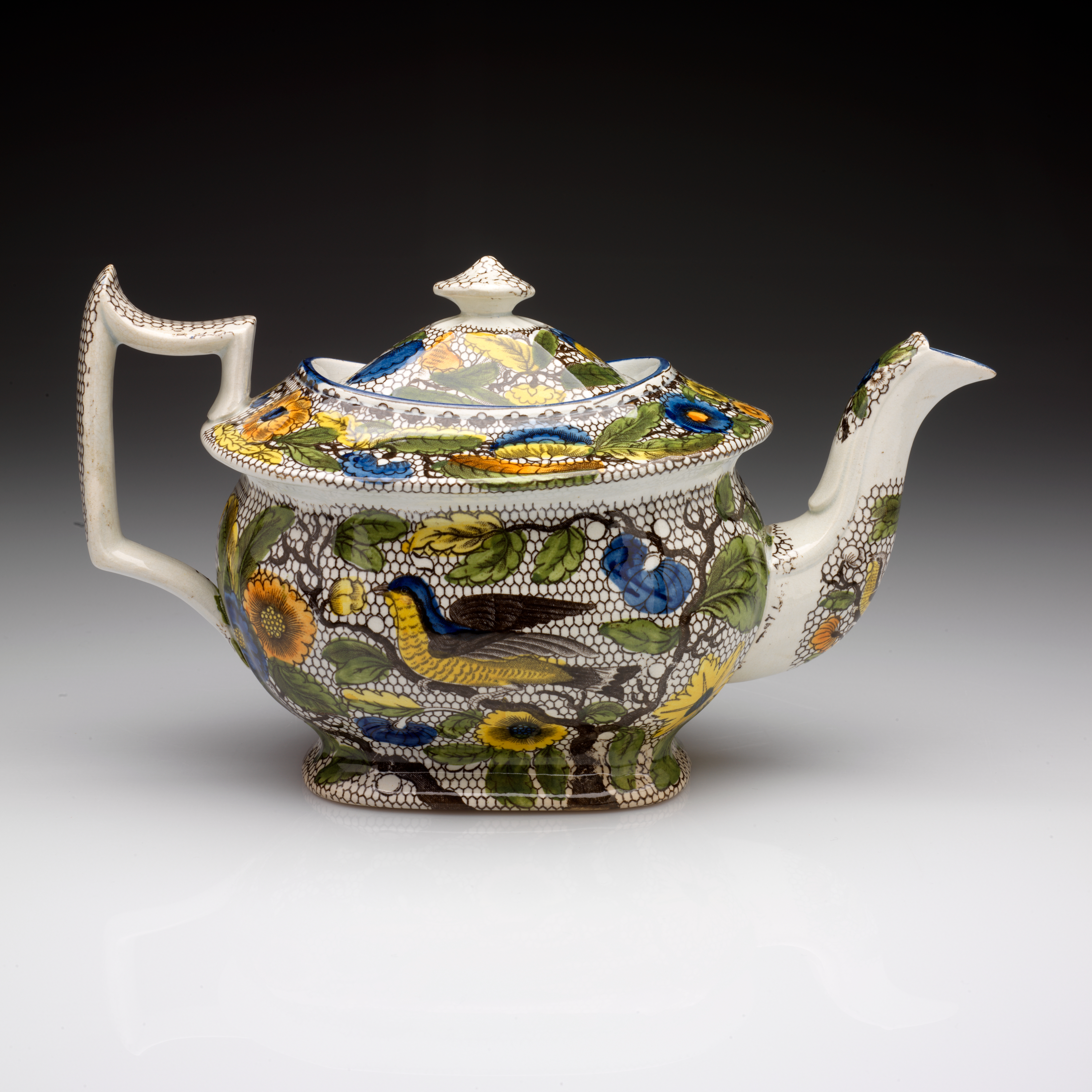 /An%20angular%20transfer-printed%20earthenware%20teapot%20with%20white%2C%20black%2C%20yellow%2C%20green%2C%20and%20blue%20decorations.