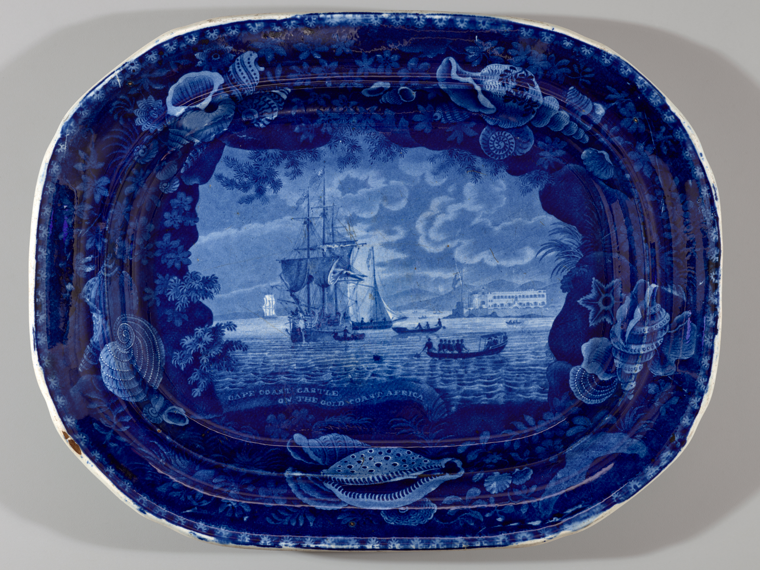 /A%20transfer-printed%20earthenware%20platter%20with%20dark%20blue%20decorations%20depicting%20a%20coastal%20scene.