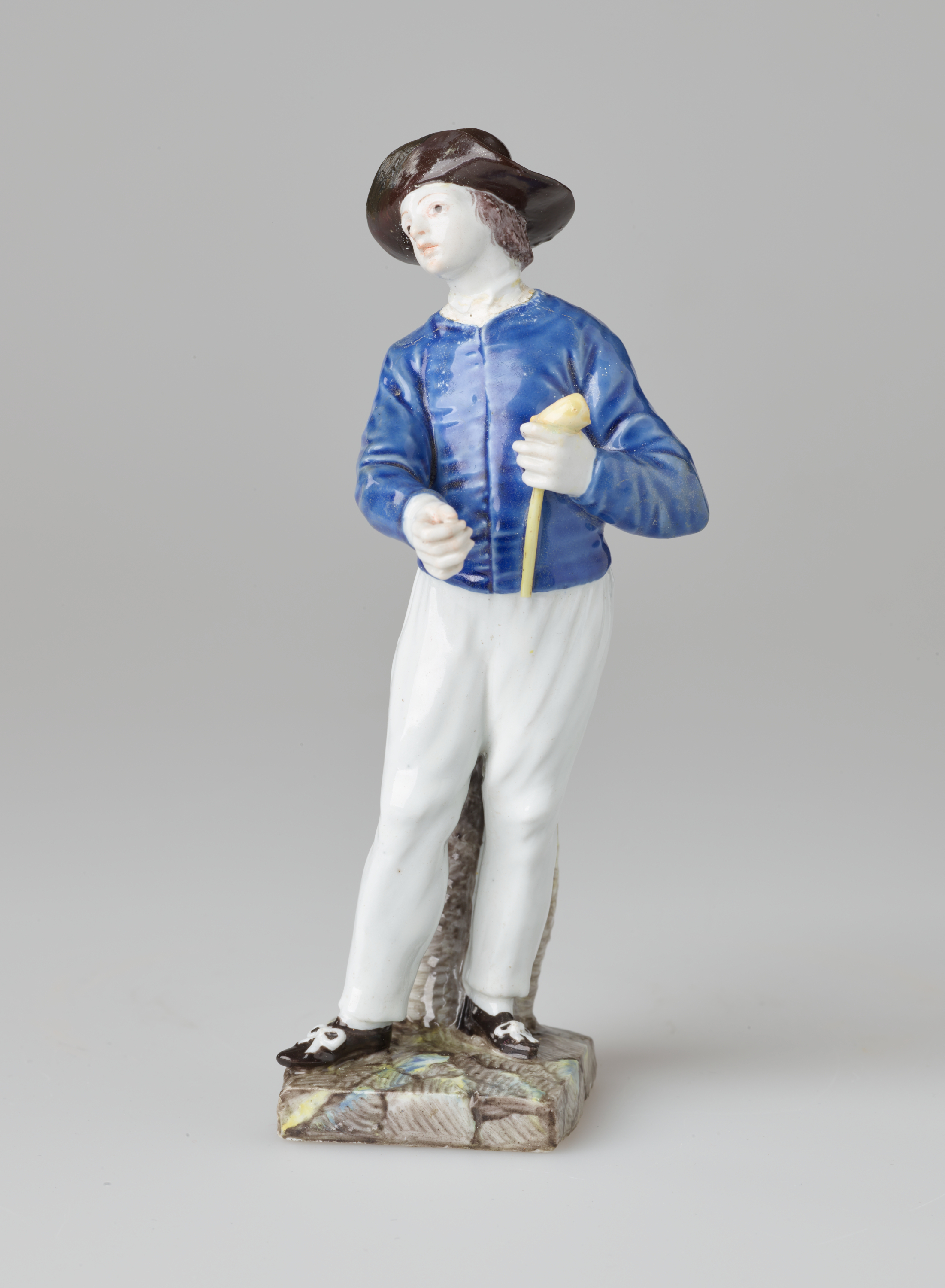 /A%20sculpture%20of%20a%20figure%20in%20historical%20clothes%2C%20a%20blue%20shirt%2C%20white%20pants%2C%20black%20shoes%20and%20hat.%20The%20figure%20is%20also%20holding%20a%20pipe.