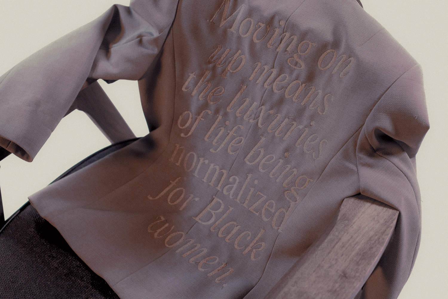 Textile blazers hung over a chair with embroidered text