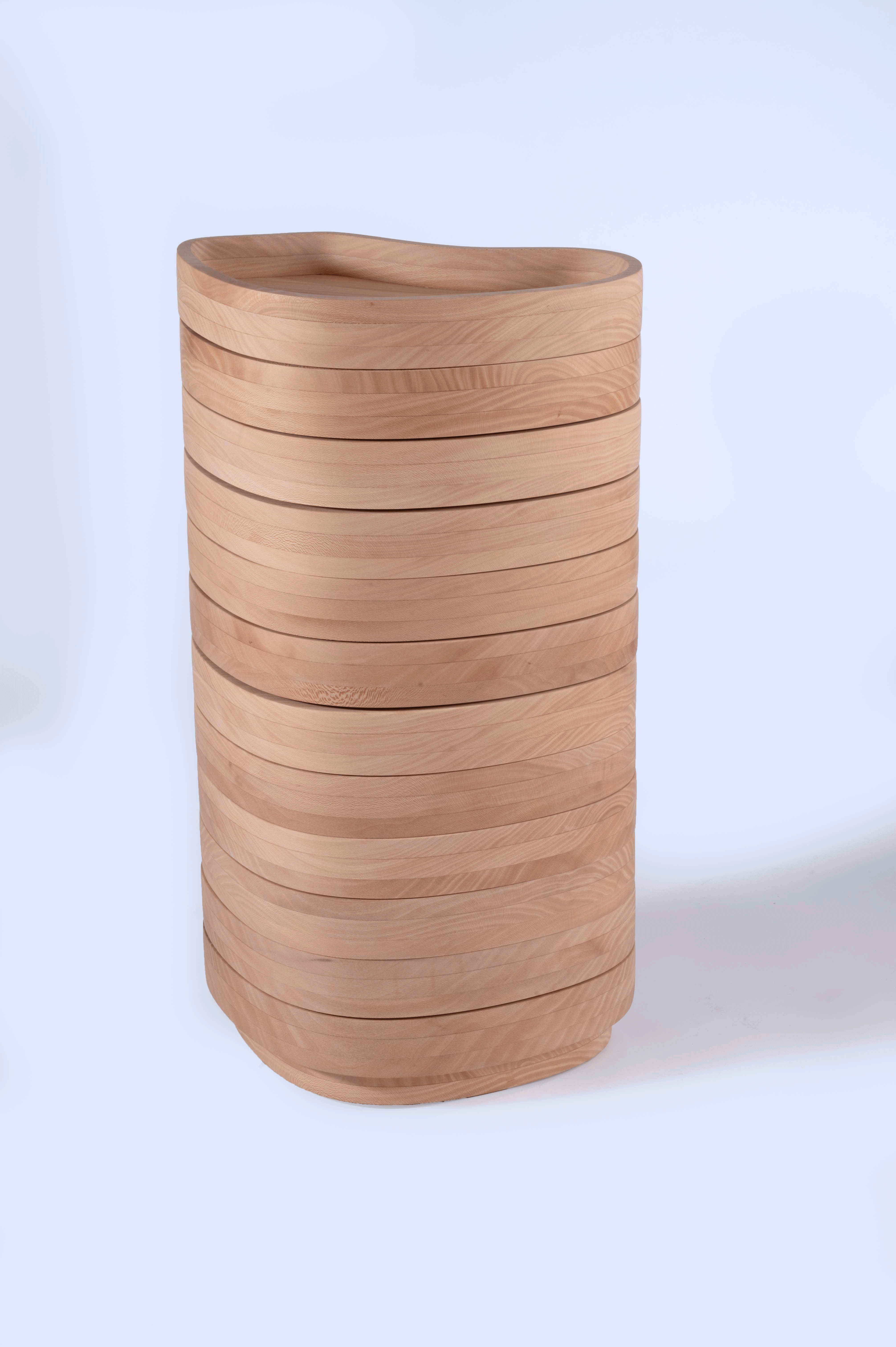 A stack of rotating wooden trays with organic, curved shapes is arranged vertically
