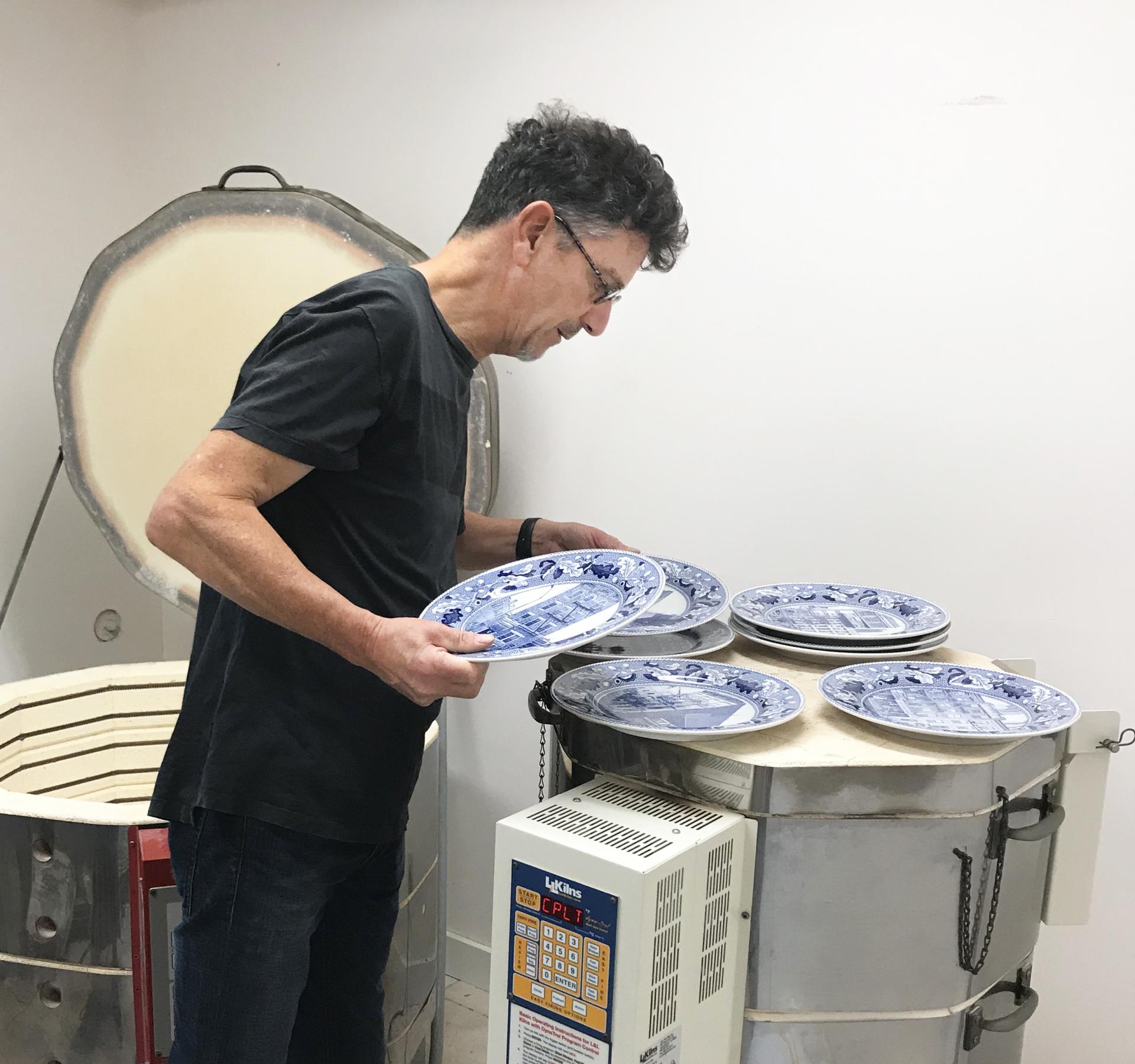 Paul Scott examines his blue and white transferware plates after they have come out of the kiln
