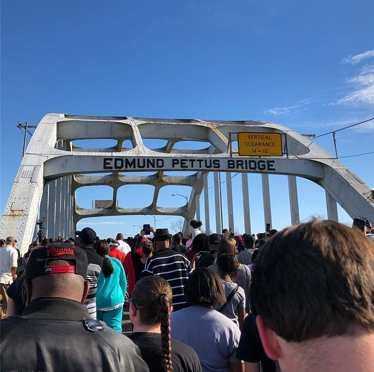 a crowd of people marching across the Edmund Pettus Bridge