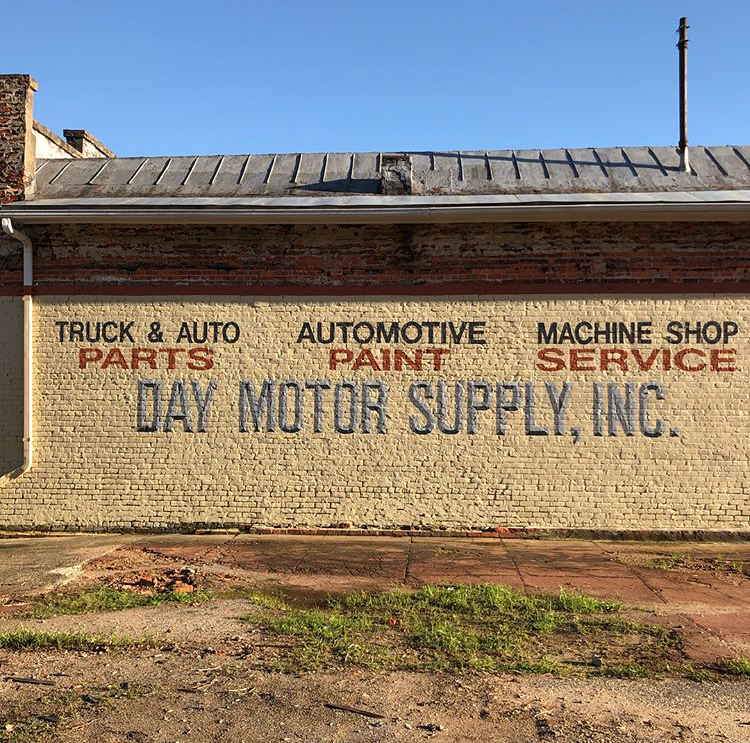 hand painted sign for a motor supply company on a brick building