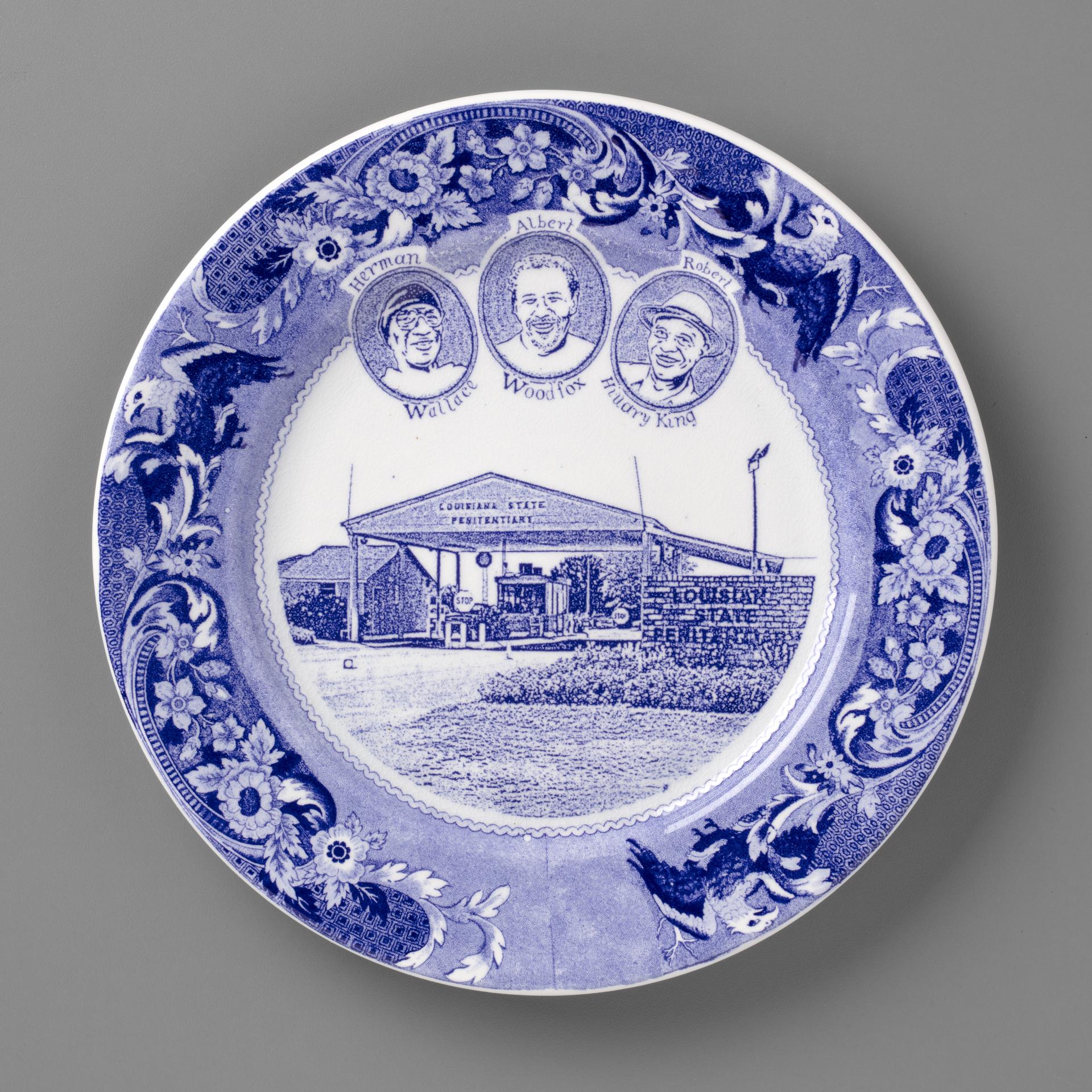 blue and white transferware plate depicting the Angola 3, and the Louisiana State Penitentary
