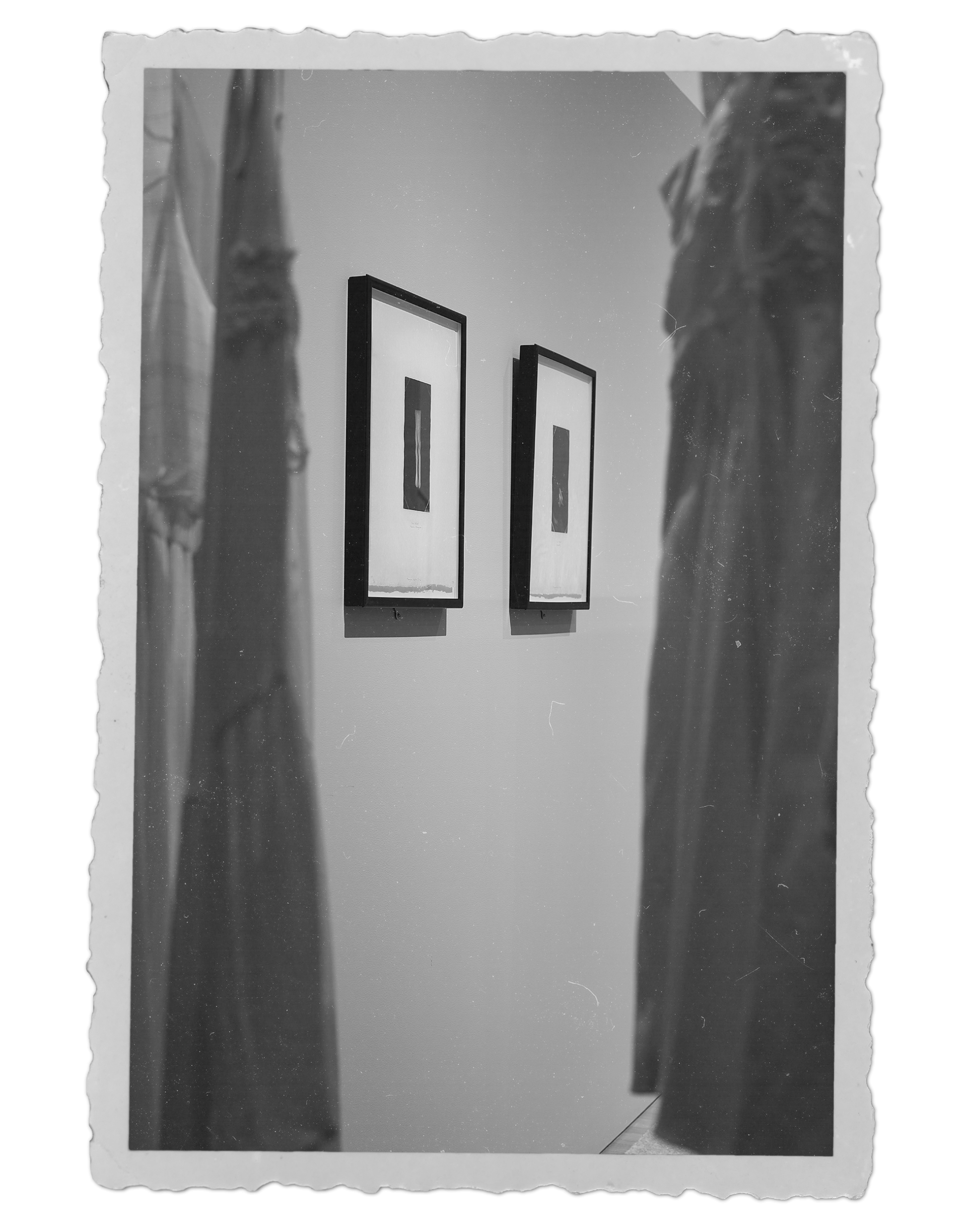 "Old" photograph of two prints by Milagros de la Torre, viewed through hanging white dresses