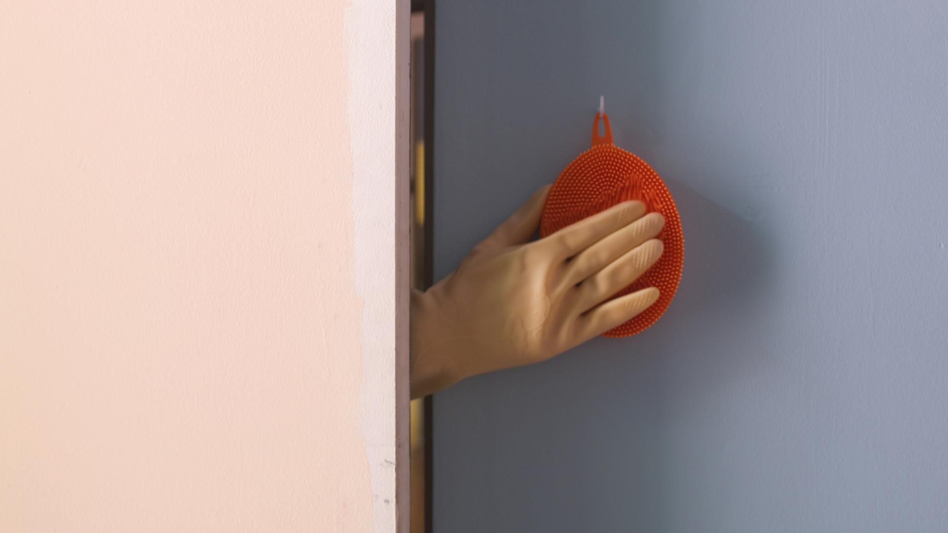 Untitled (Studio) still, gloved hand touching a silicone kitchen brush