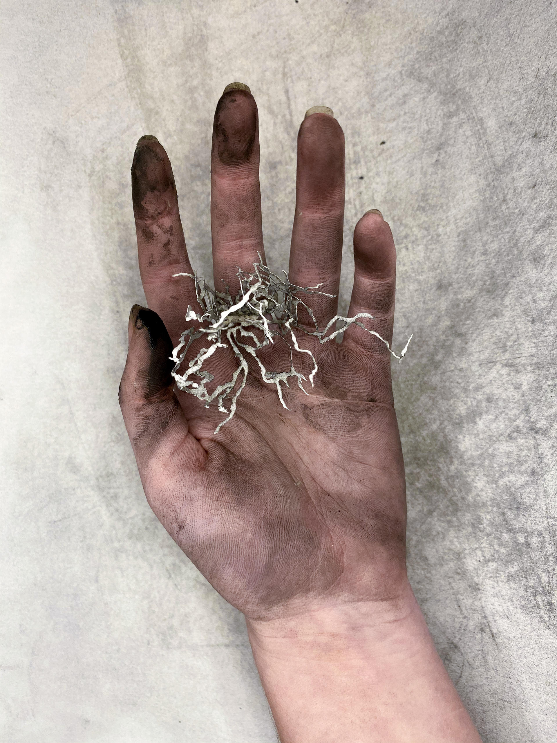 Hand covered in ash holding a small paper sculpture