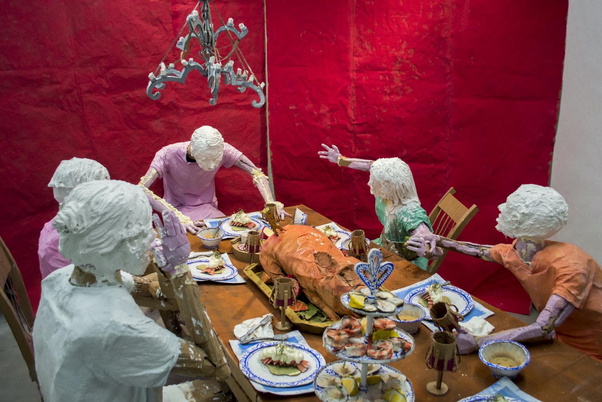 Installation sculpture of a group of people sitting around a dinner table.