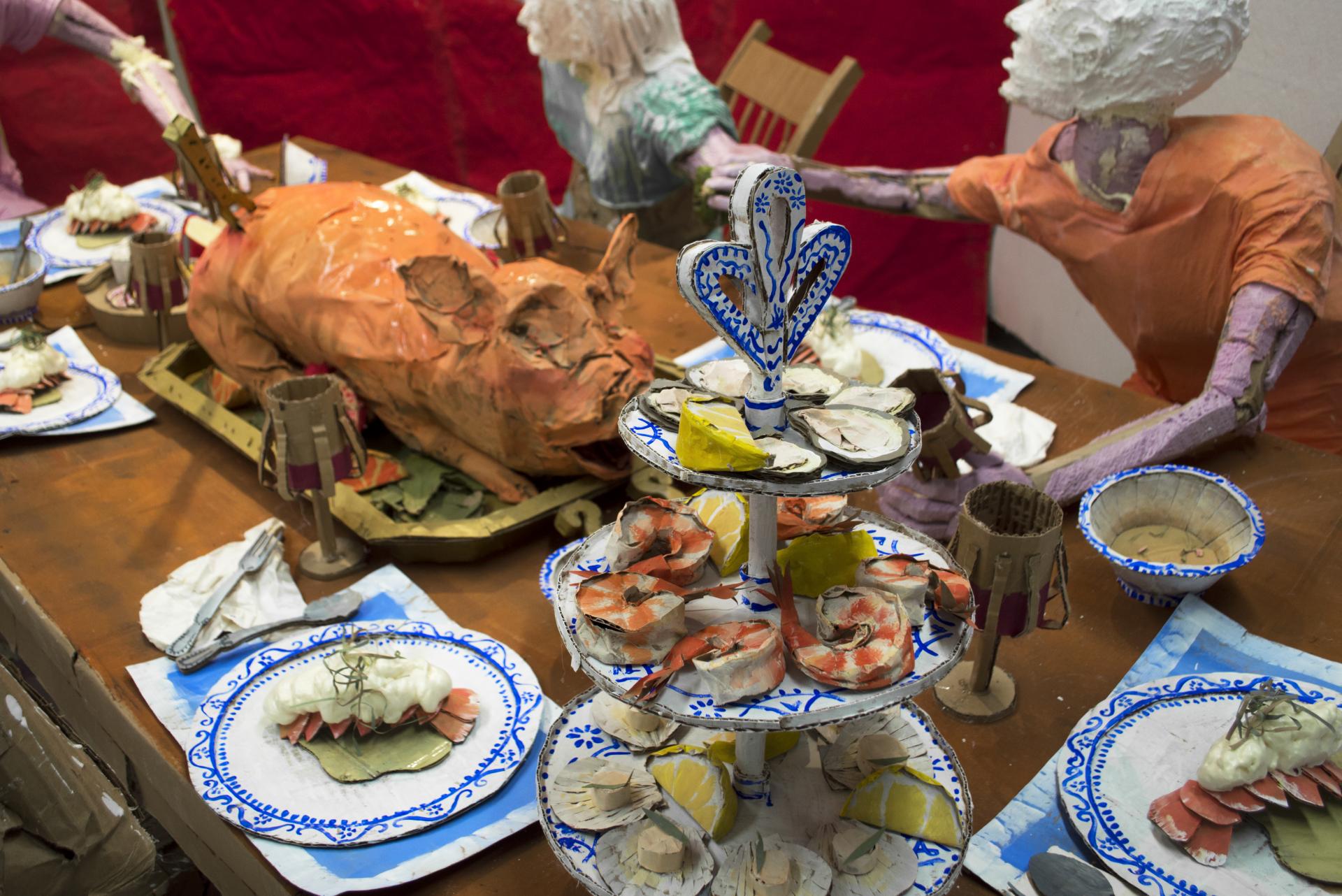 Installation sculpture of a group of people sitting around a dinner table.