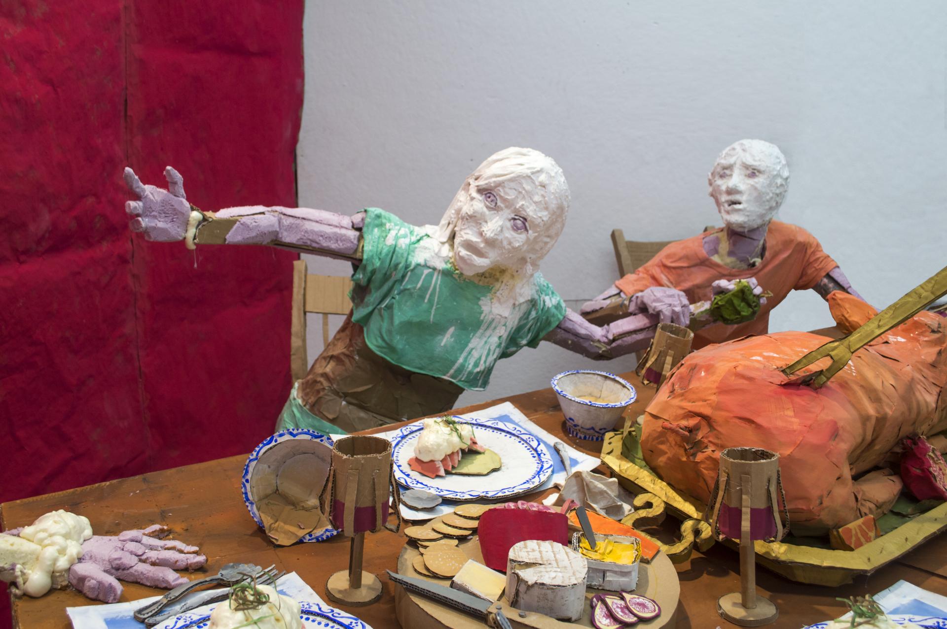 Installation sculpture of a group of people sitting around a dinner table.