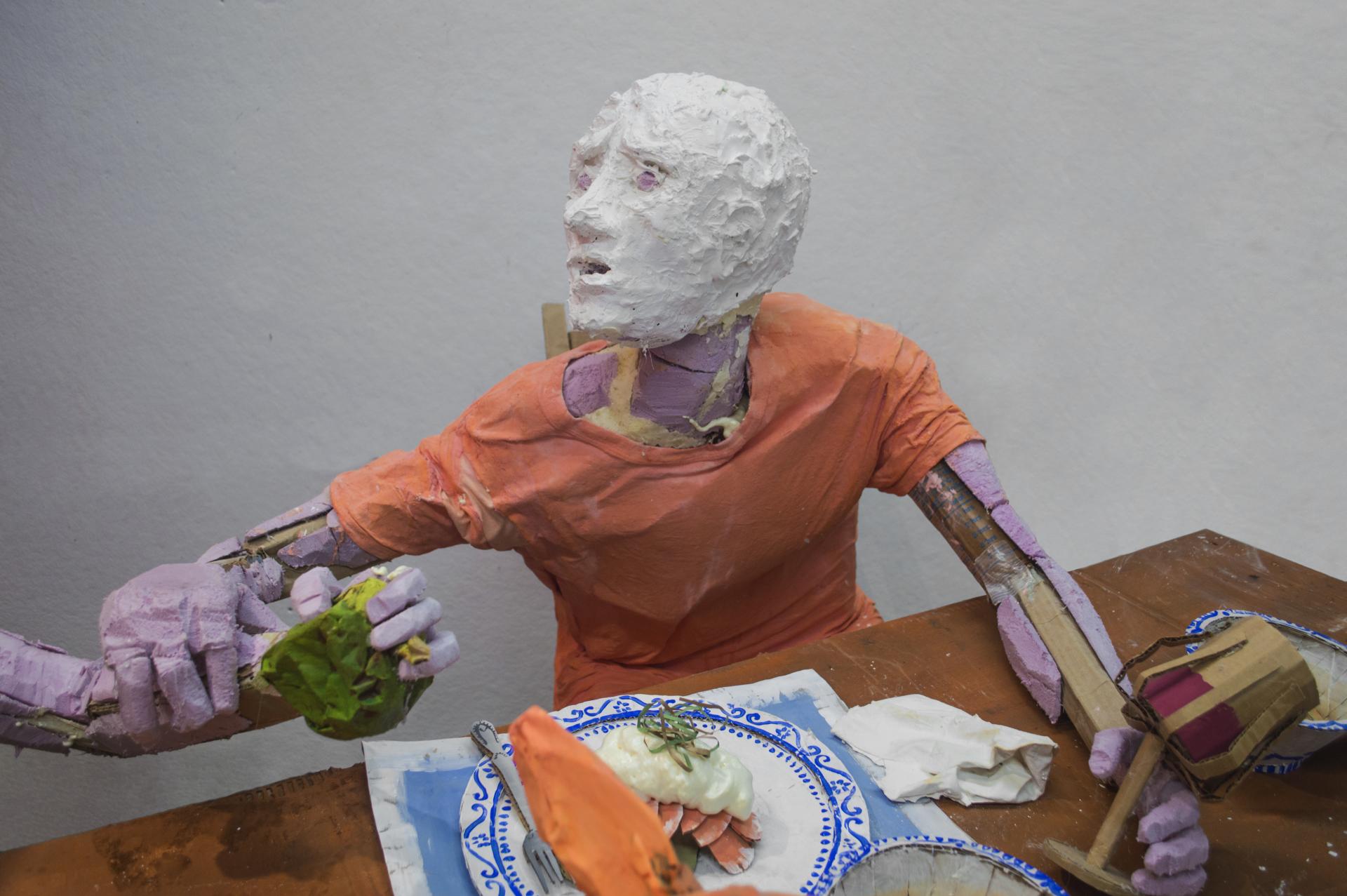 Installation sculpture of a group of people sitting around a dinner table.