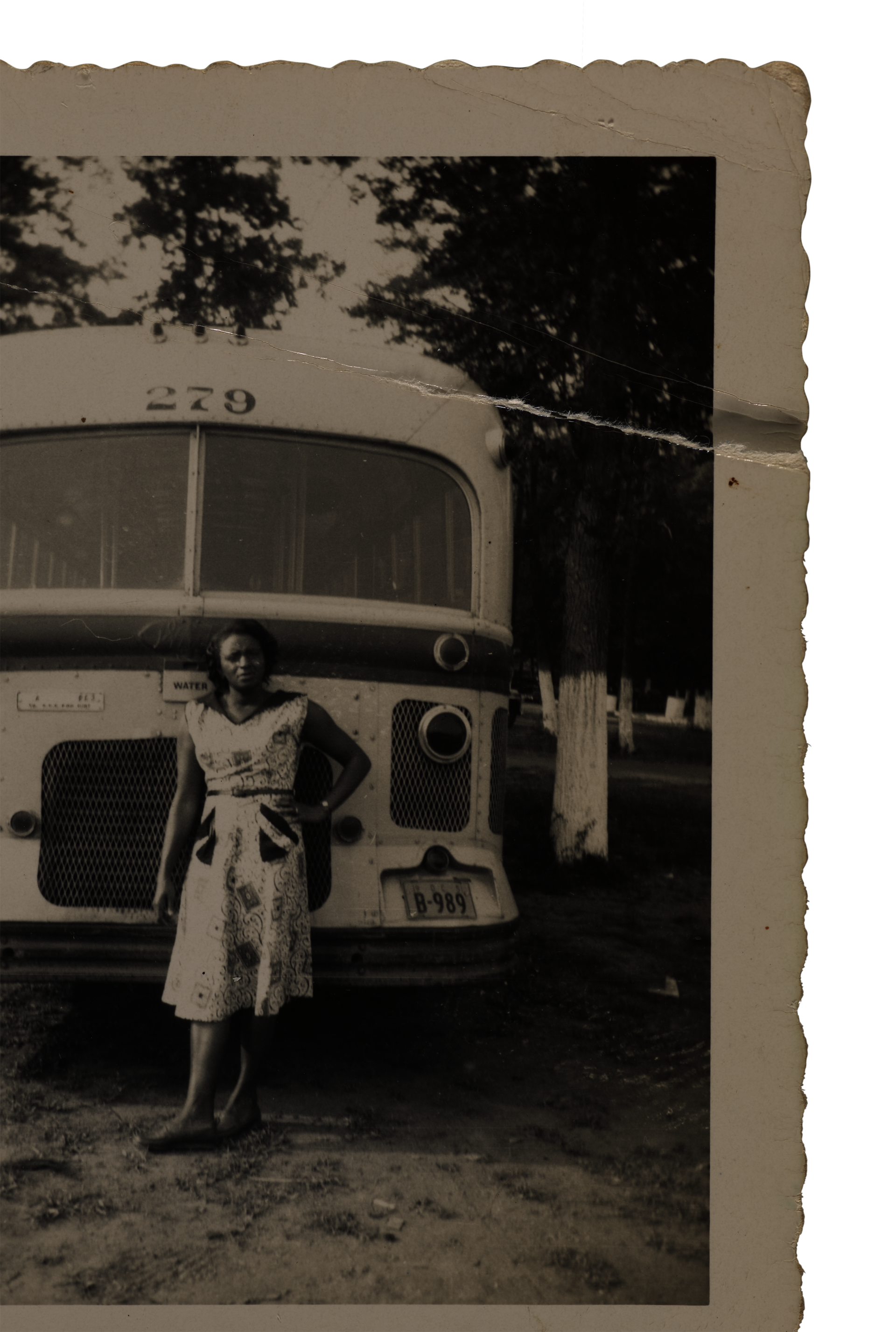 Black and white snapshot of a woman standing in front of a bus