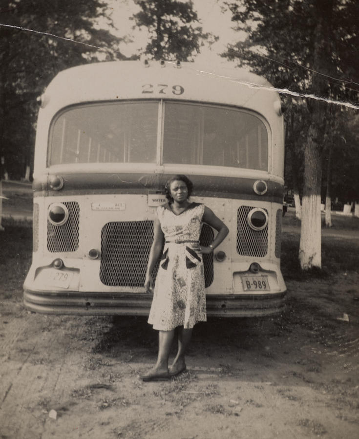 1940s black and white picture of a Black woman standing casually in front of a bus