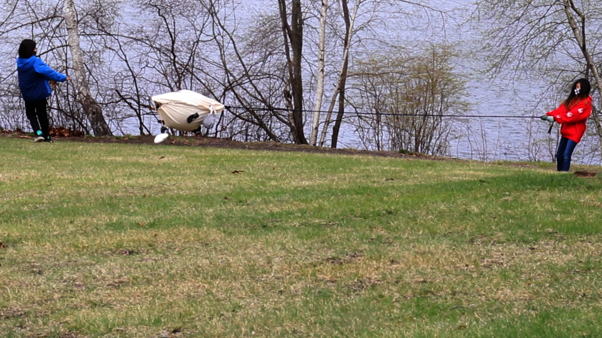 Two kids each pull on the ends of a rope, suspending a large toy between them.