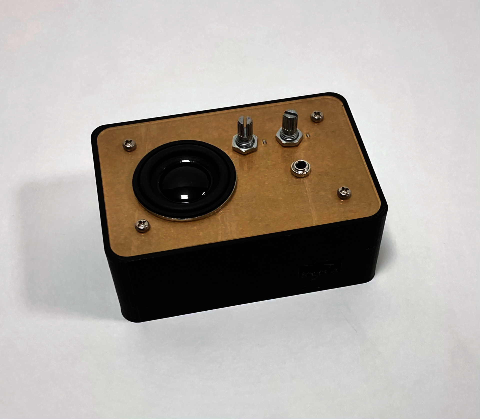 An instrument enclosed in a black plastic box, with a small speaker and two knobs visible on the top face.