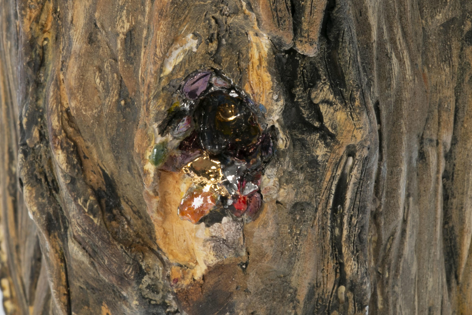 Detail of ceramic firewood sculpture depicting hole with sparkling confetti spilling out in wood.