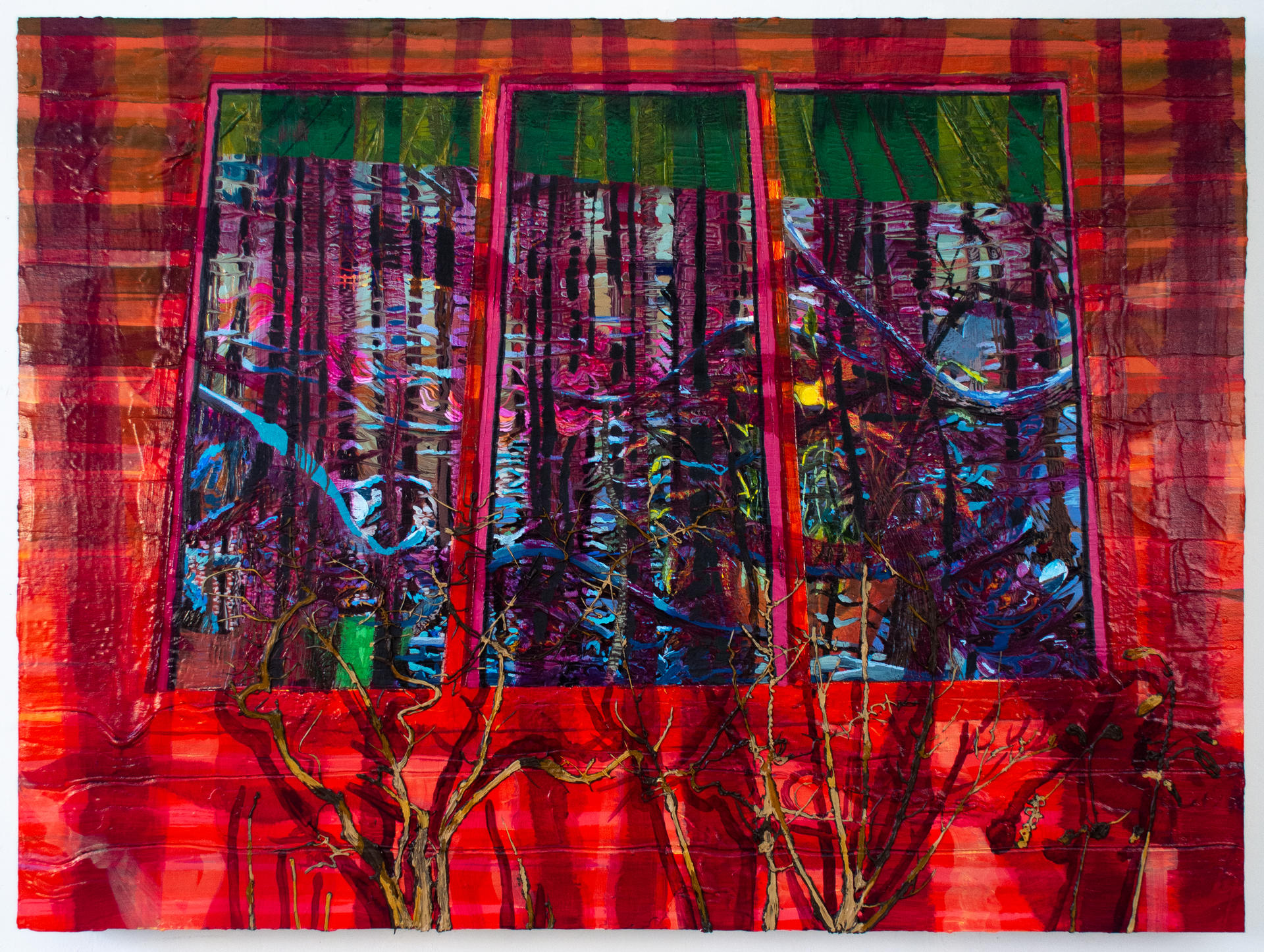 A exterior window of a red barn reflects a winterscape of snow covered trees