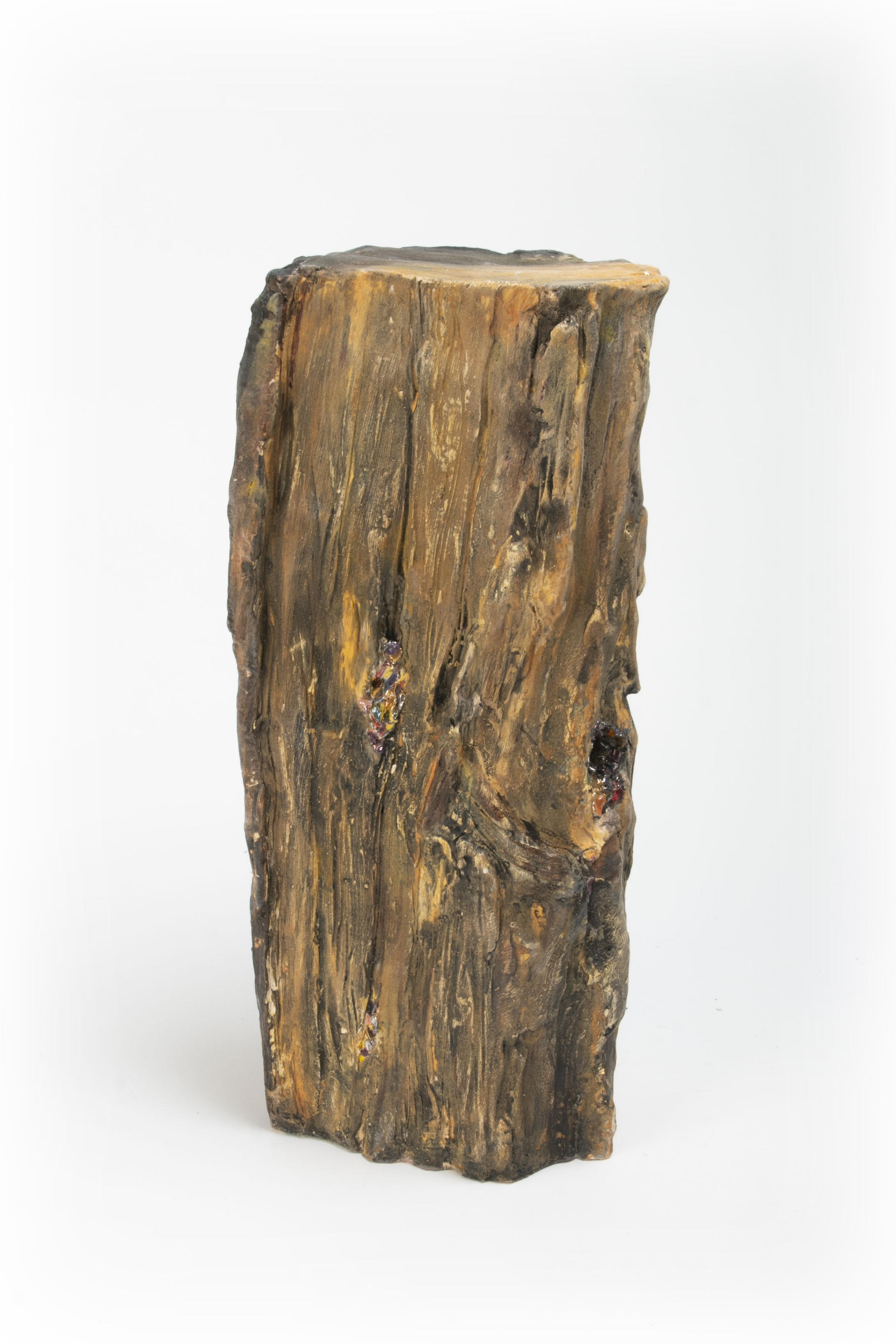 Ceramic sculpture resembling fire wood with shiny confetti spilling out of cracks and knots in wood.