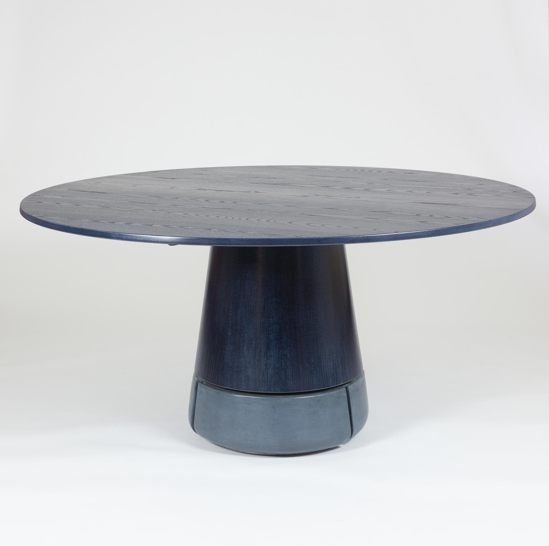 Blue round dining table with concrete base.