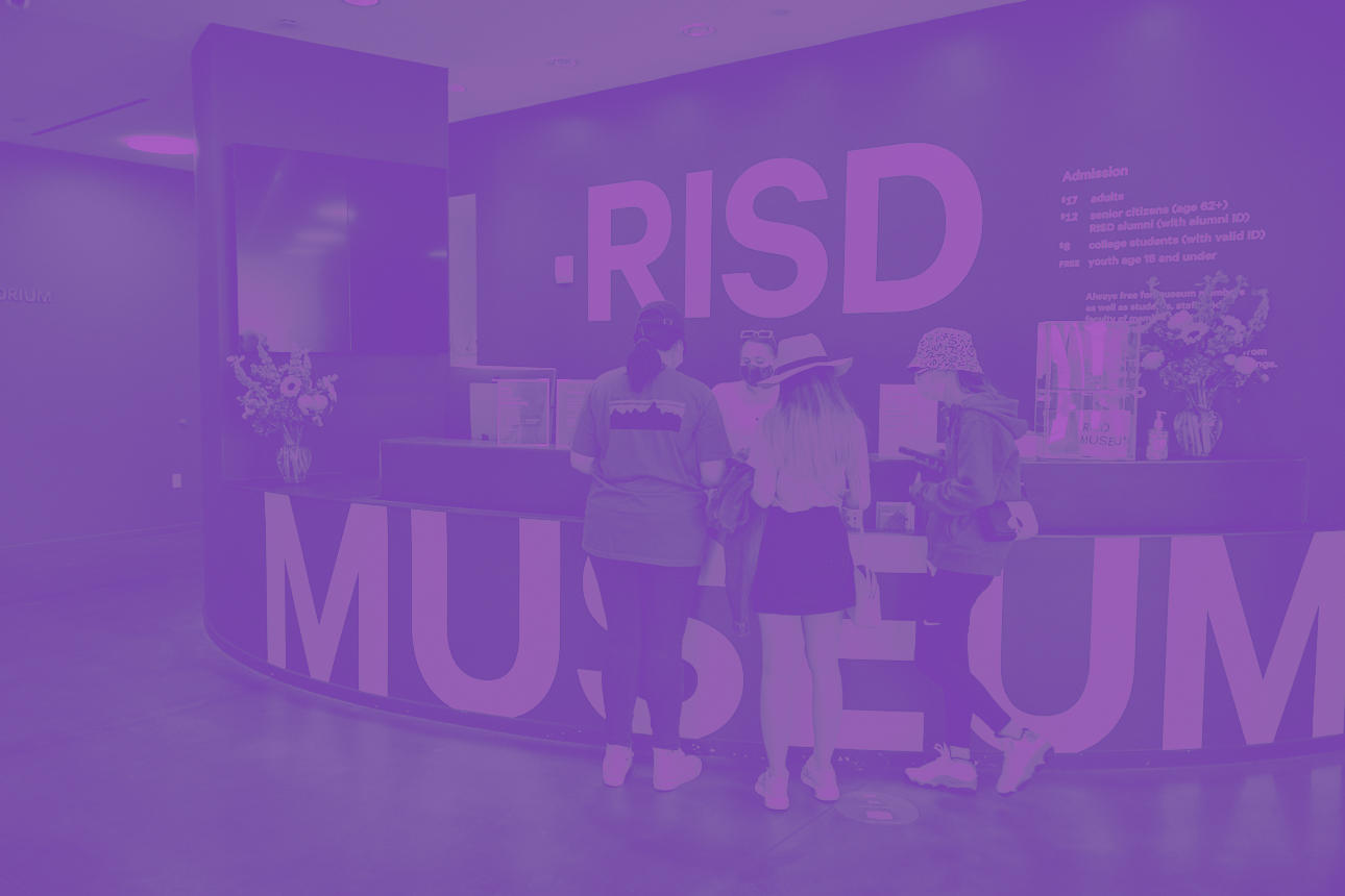 All-purple photo of visitors standing at the museum’s front desk. The words “RISD Museum” are incorporated into the design of this area.