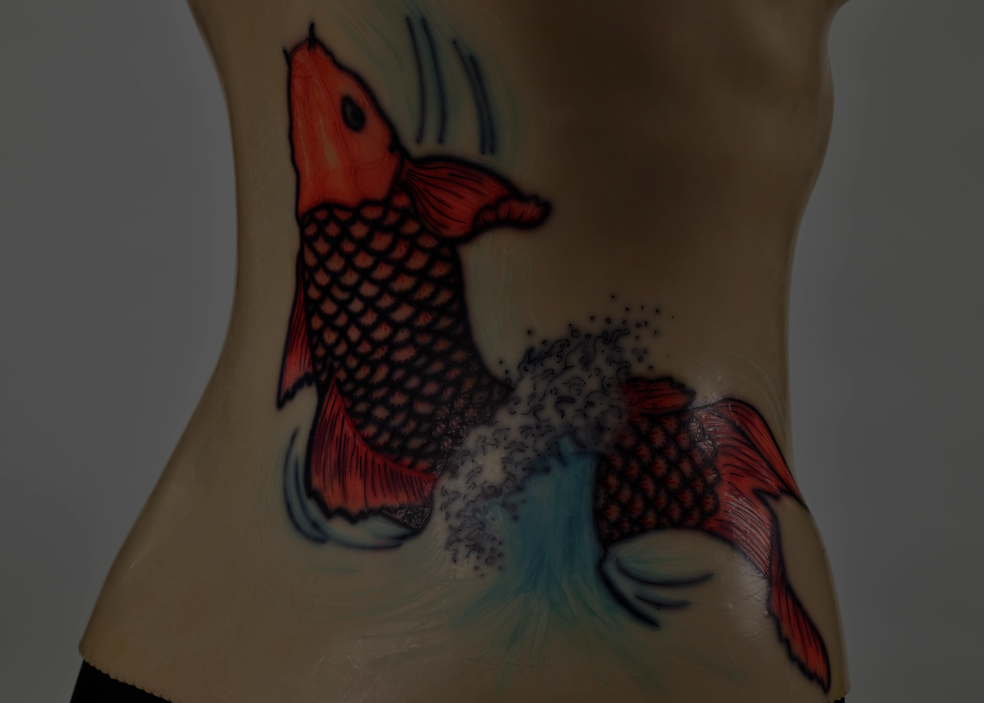 An off-white back brace is molded onto a black mannequin torso. The plastic brace attaches down the middle of the torso. A red koi design decorates the right side.