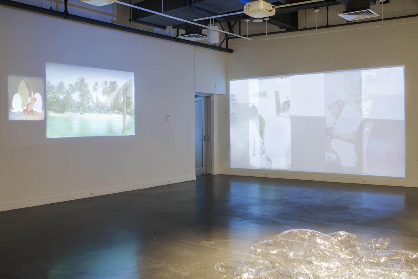 gallery interior; two walls display faintly projected images