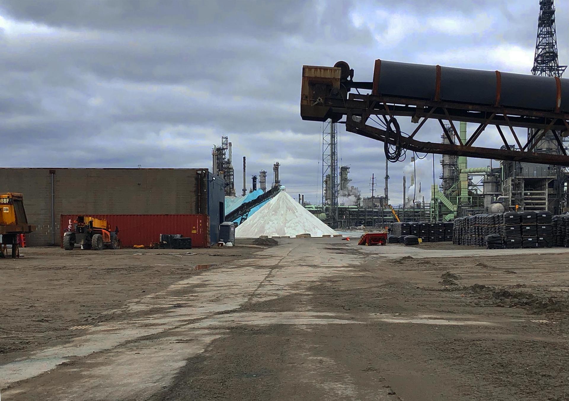 A photograph of some of the facilities of the Detroit Salt Co.  including mining equipment, heavy machinery, and stockpiles of road salt.