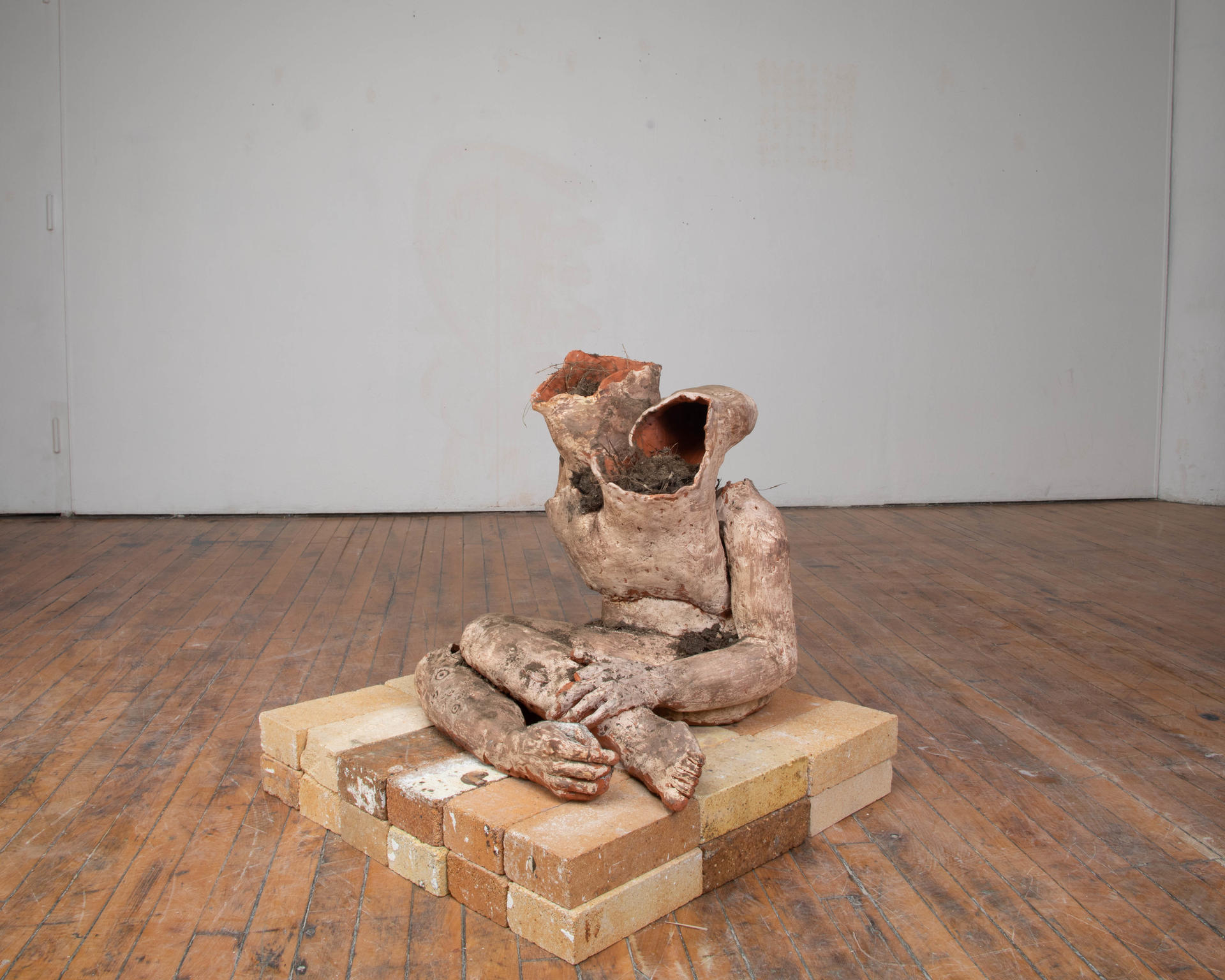 An abject terracotta body filled with soil seated on bricks 