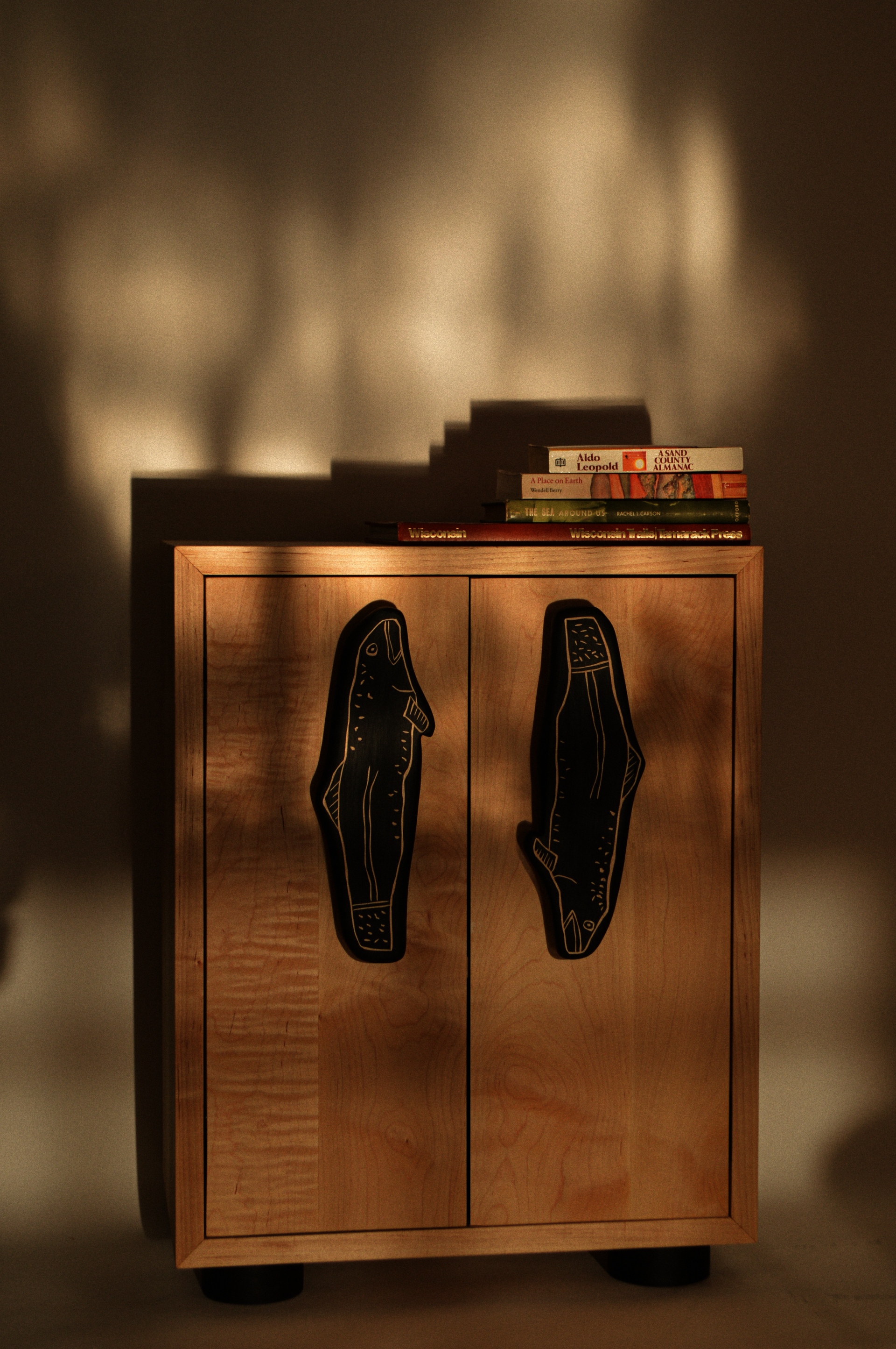 a small solid maple cabinet with oversized handles shaped like fish
