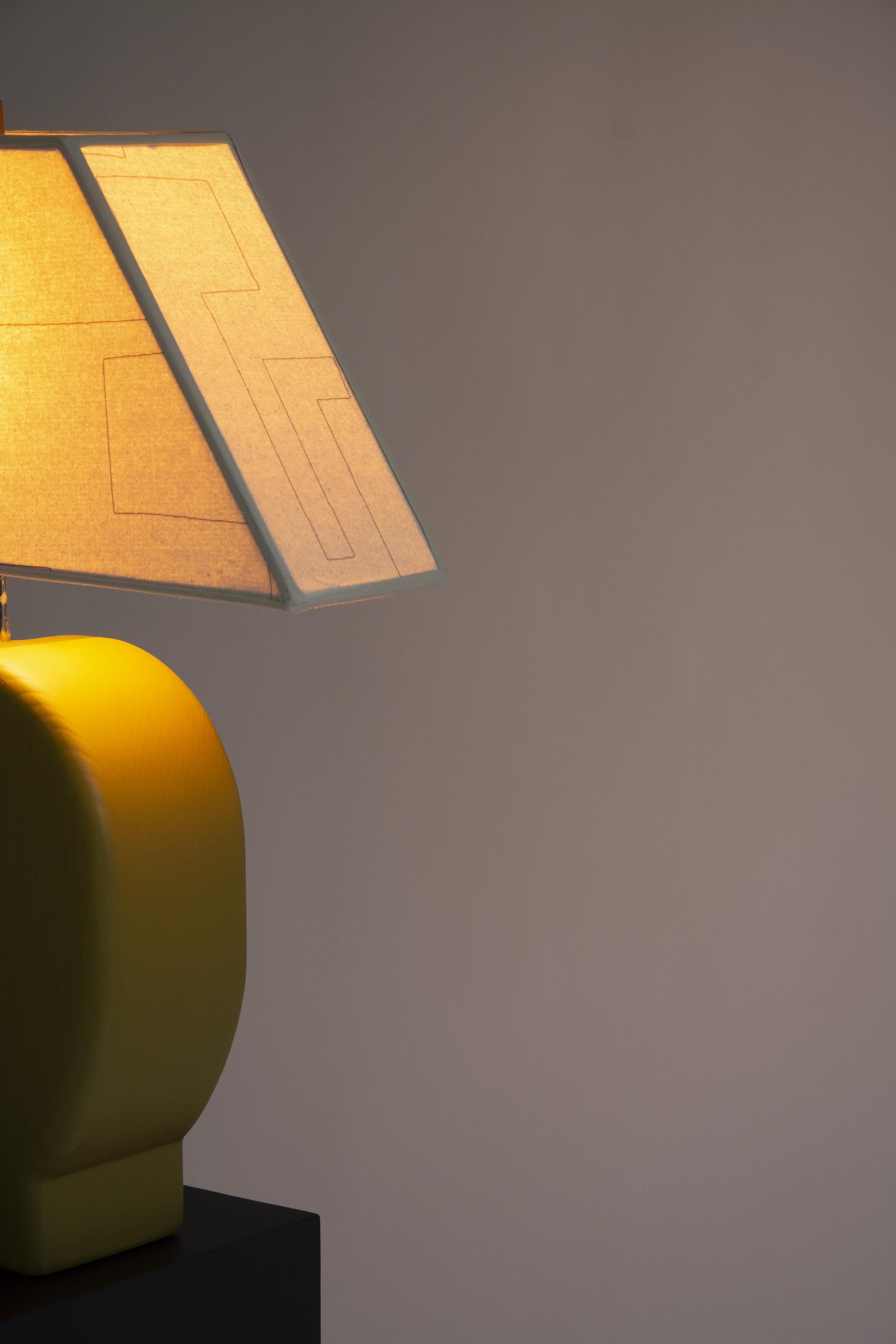 Detail view of Sister Lamp turned on, with an orange glow coming through the canvas shade.