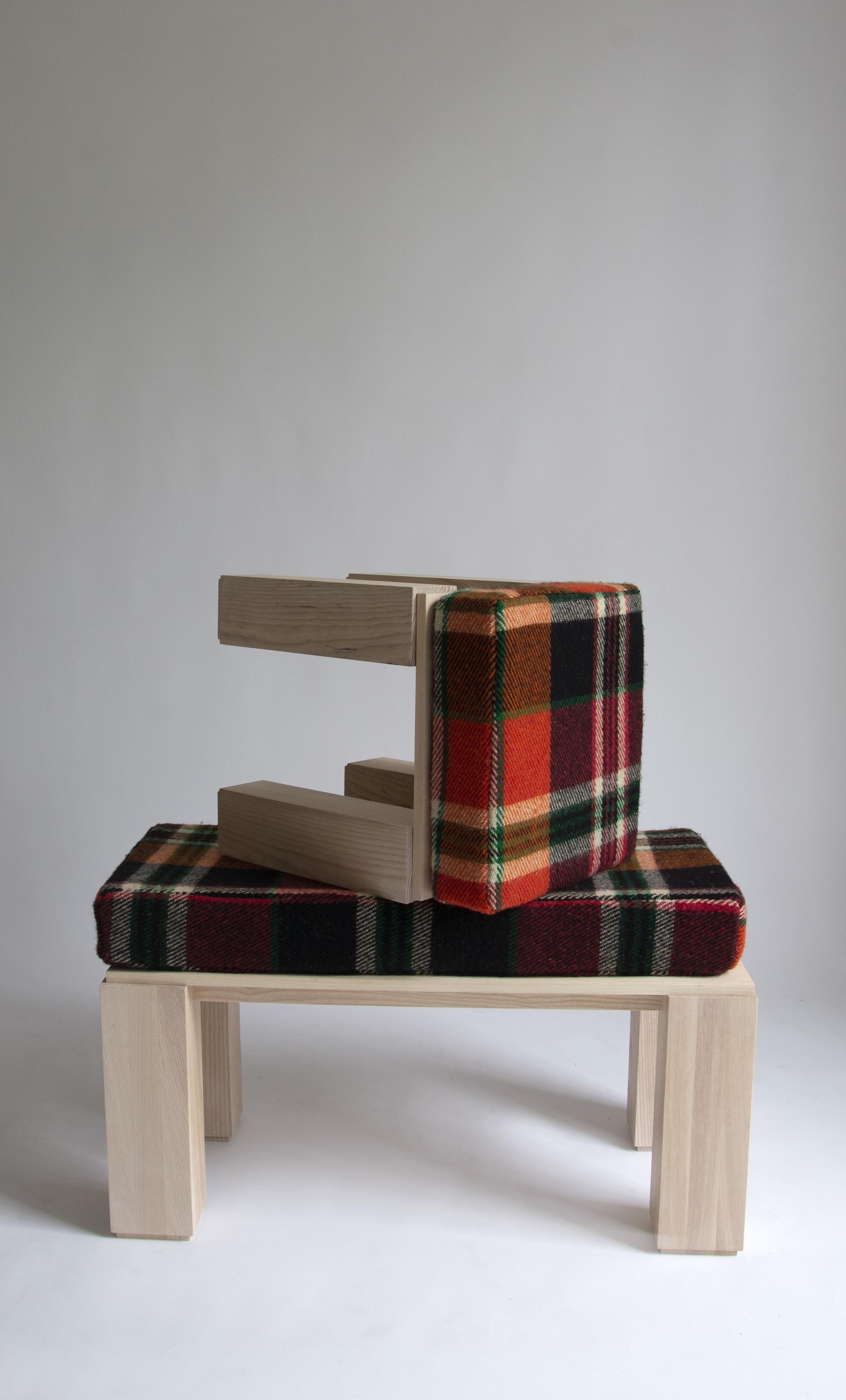 Wooden stool with orange, green and red plaid wool cushion sits kneeled on top of wooden bench with same plaid cushion.  