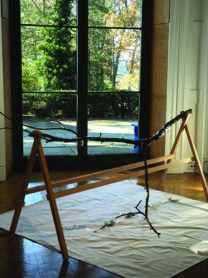 Tree branch coated in glass shell; seated on sawhorses.