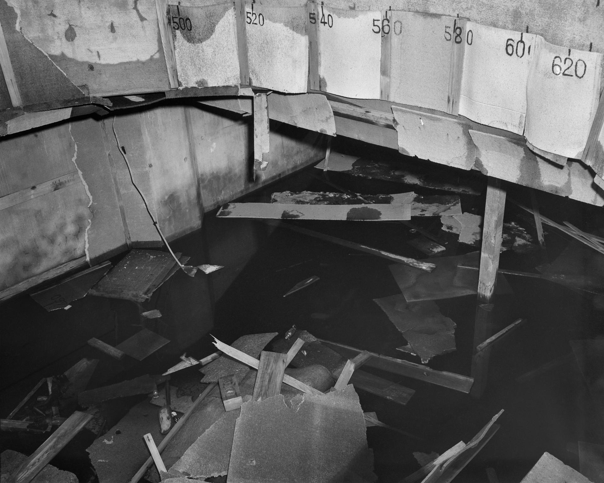 A black-and-white flash-lit photograph of a flooded enclosure, captured by the United States military at the end of World War II in the Pacific.