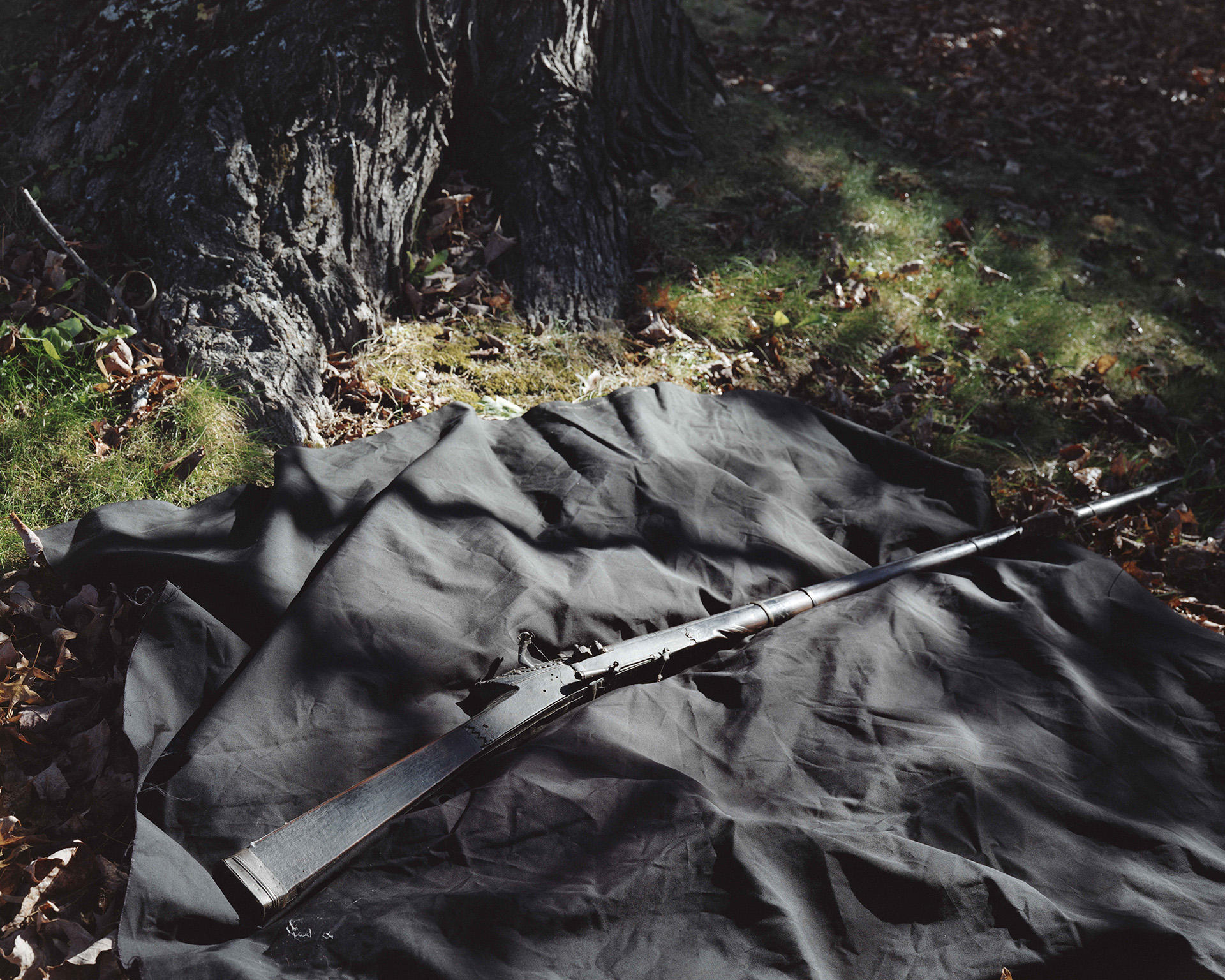 Photograph of a rifle laid on a piece of fabric on grass.