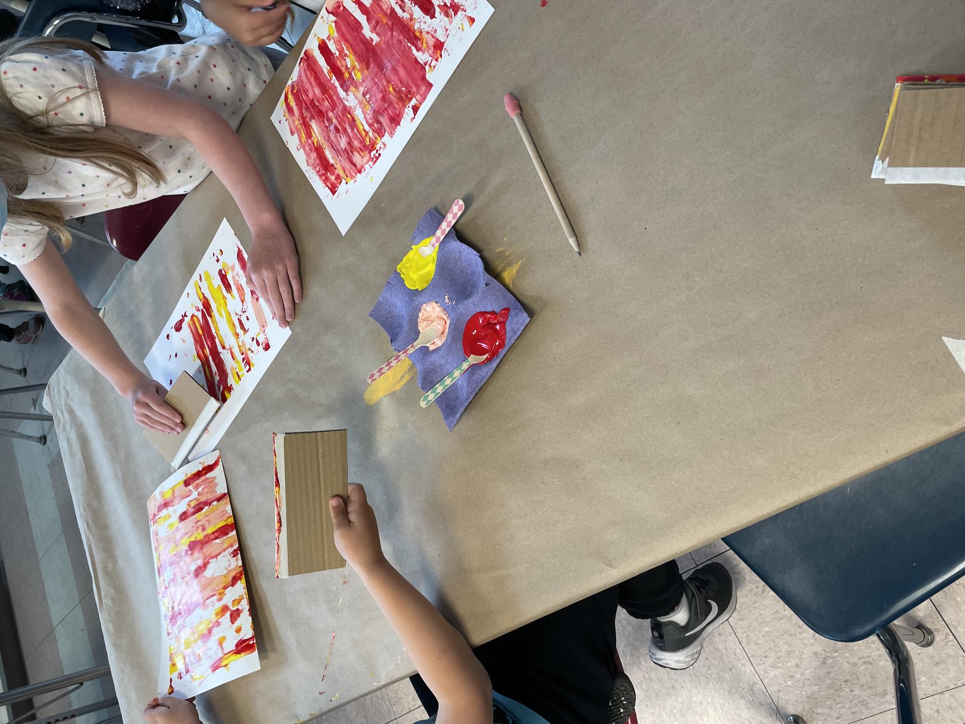 Students applying paint using wooden spoons and spreading it out to created the squeegee effect.  